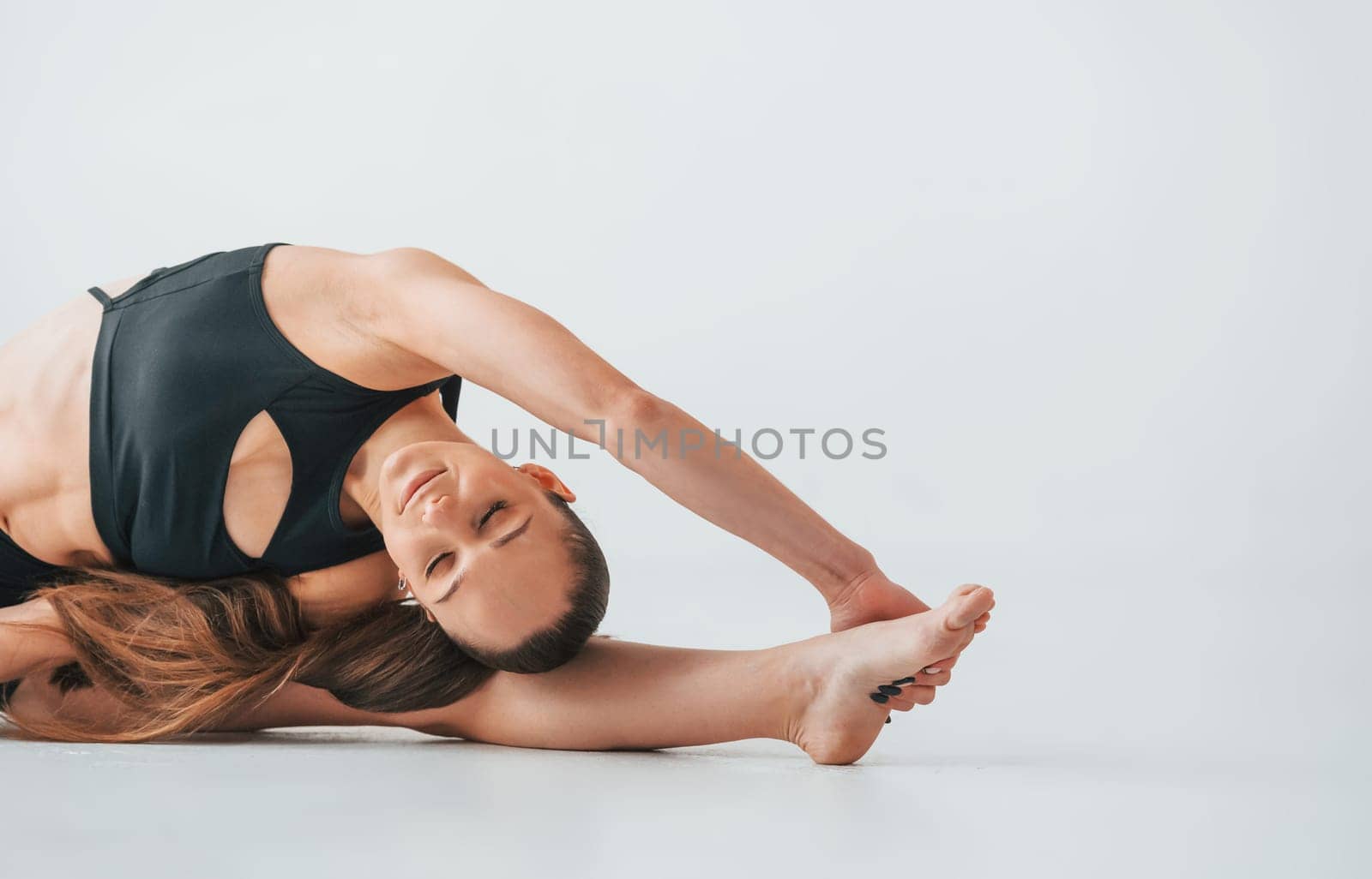 Professional trainer. Young woman in sportive clothes doing gymnastics indoors.
