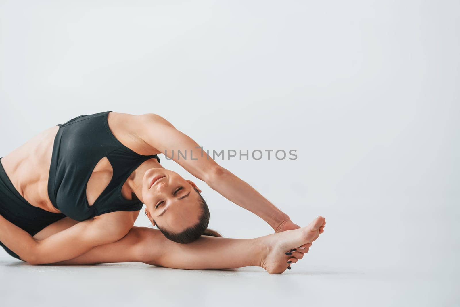 Professional trainer. Young woman in sportive clothes doing gymnastics indoors.