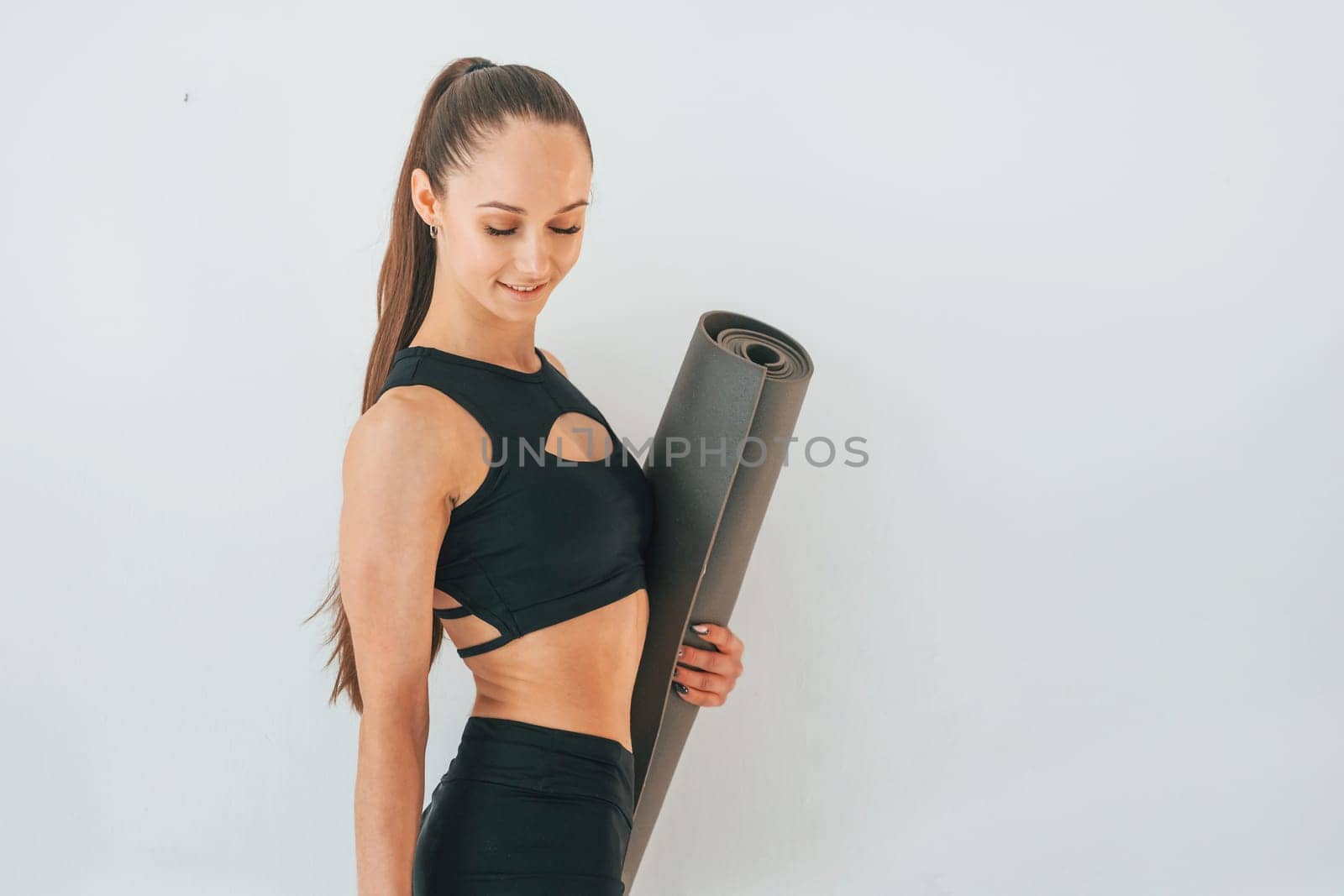 Ready for the exercises. Young woman in sportive clothes doing gymnastics indoors.