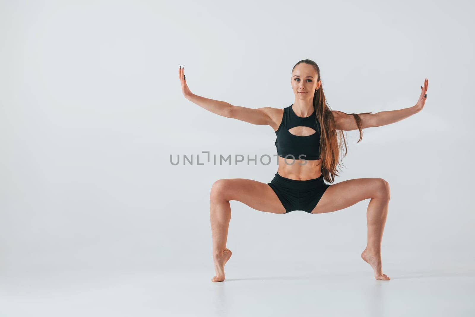 Young woman in sportive clothes doing gymnastics indoors.