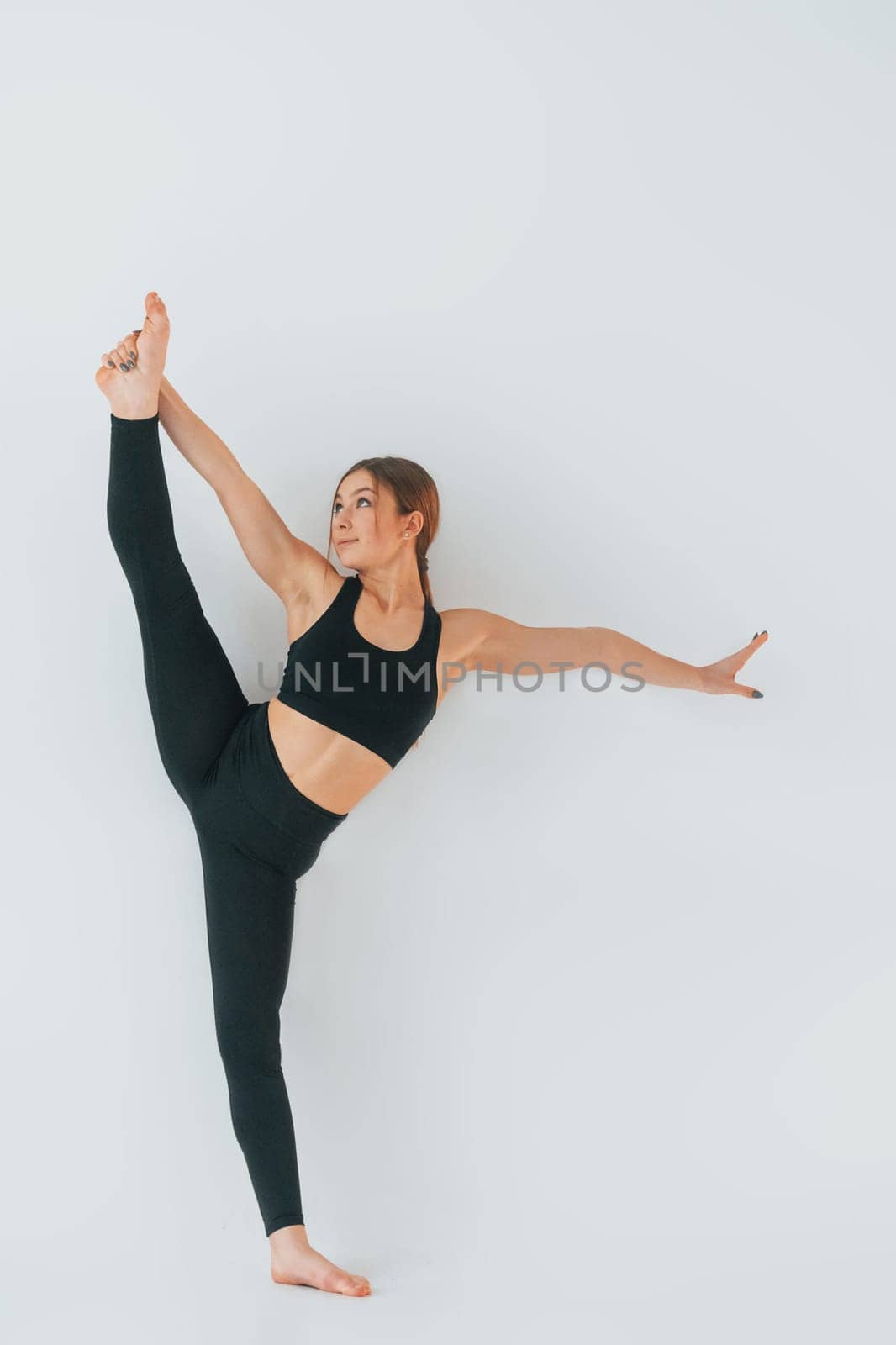 Young woman in sportive clothes doing gymnastics indoors.