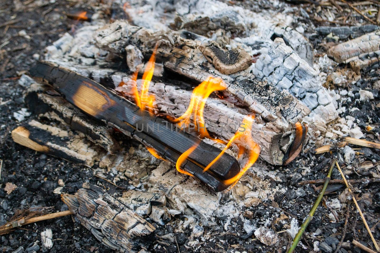 A fire burns in a campfire with a red fire in the background. High quality photo