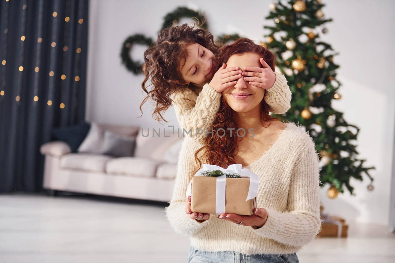 Making surprise. Mother with her little daughter is at home. Christmas decorations.