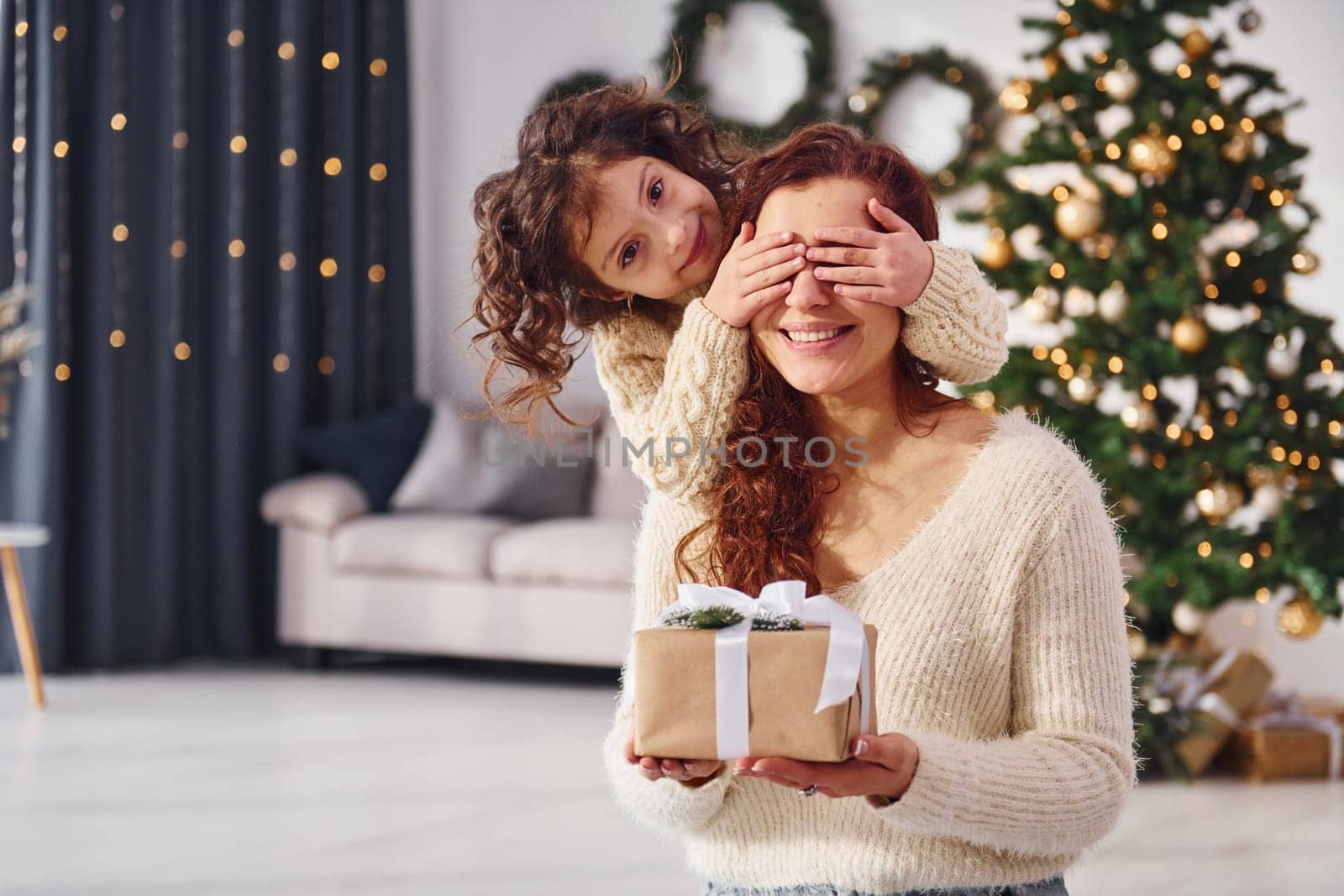 Making surprise. Mother with her little daughter is at home. Christmas decorations.