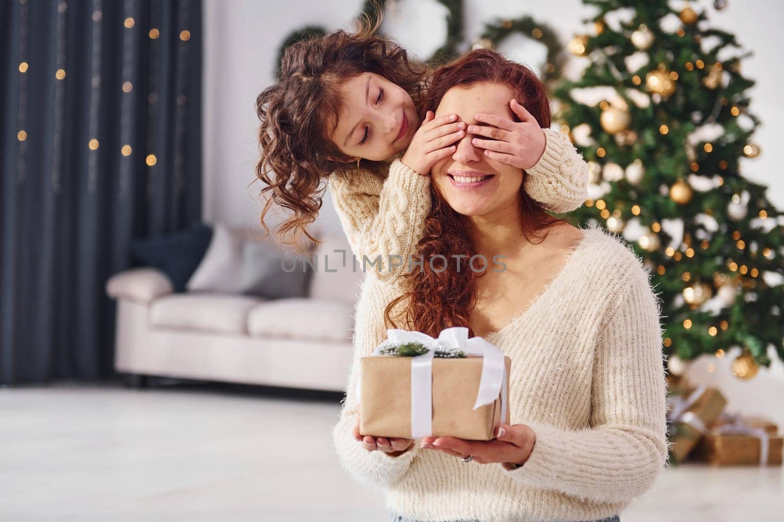 Making surprise. Mother with her little daughter is at home. Christmas decorations.