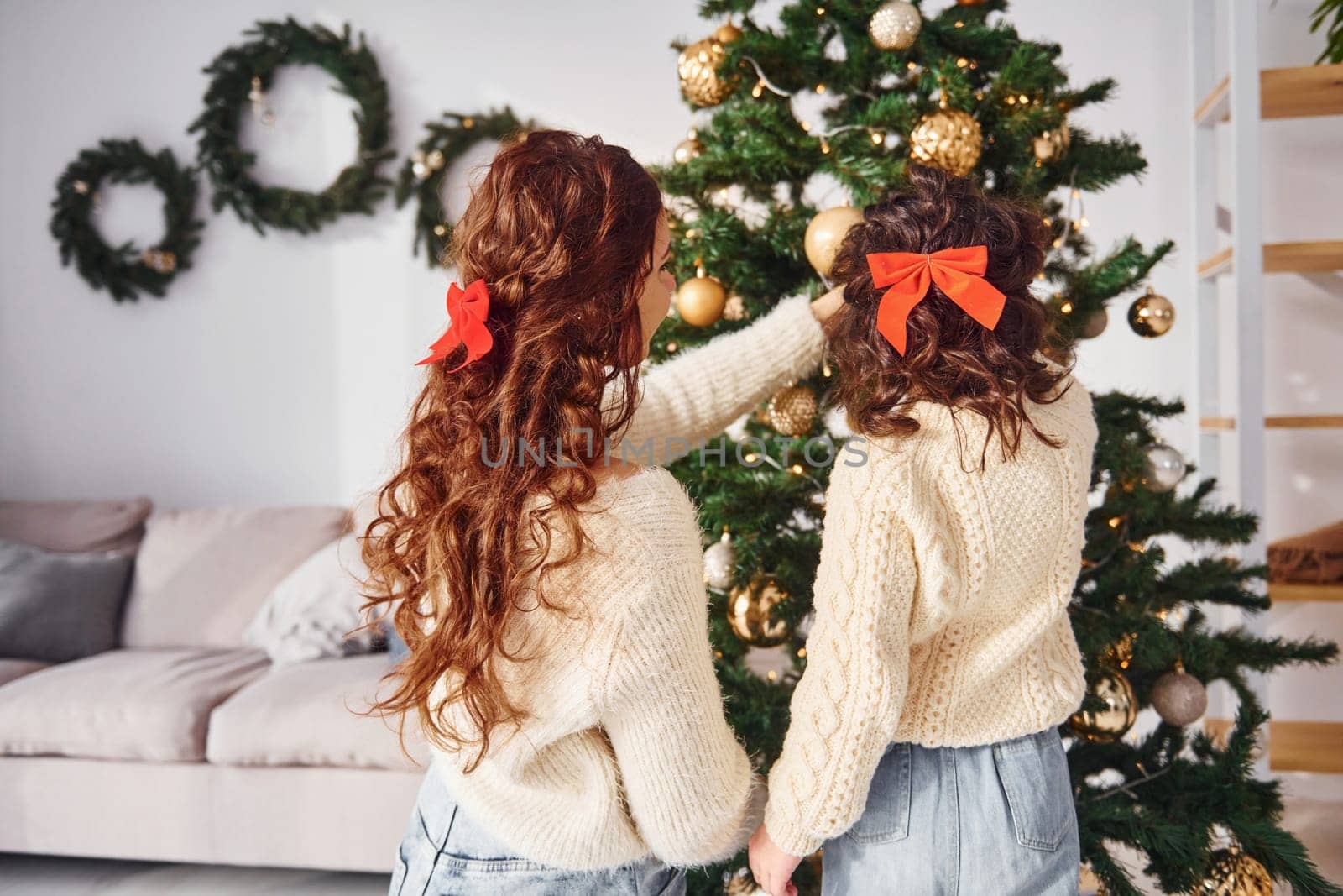 Decorating tree. Mother with her little daughter is at home.