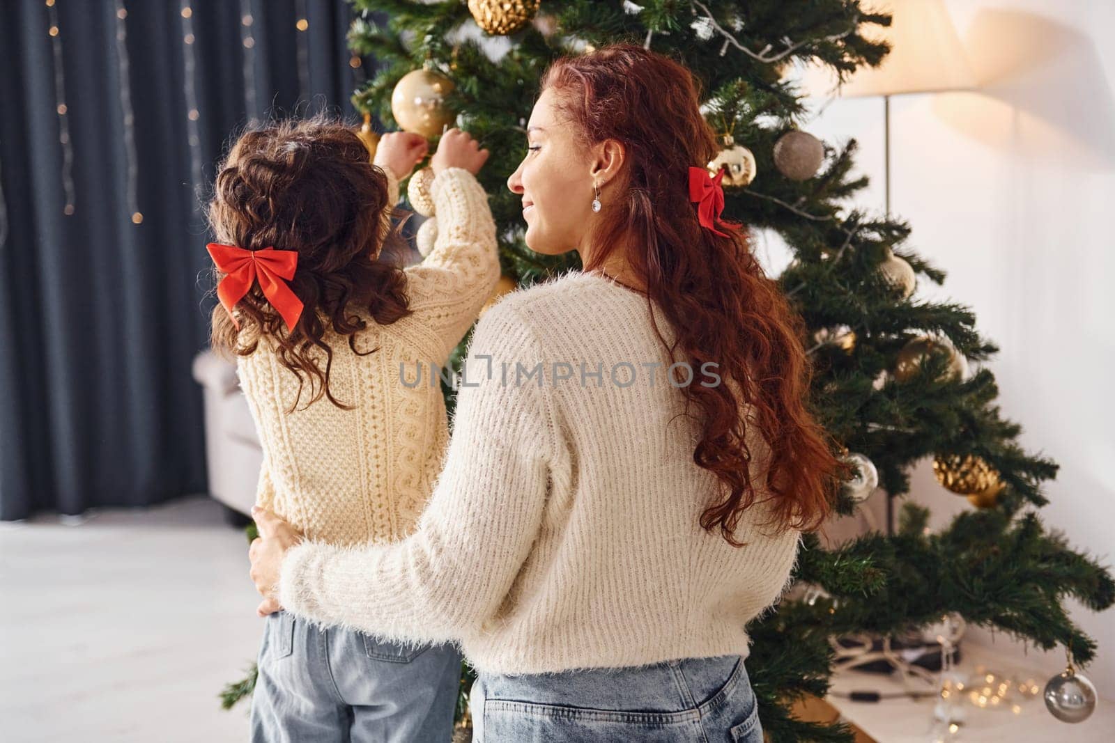 Decorating tree. Mother with her little daughter is at home.