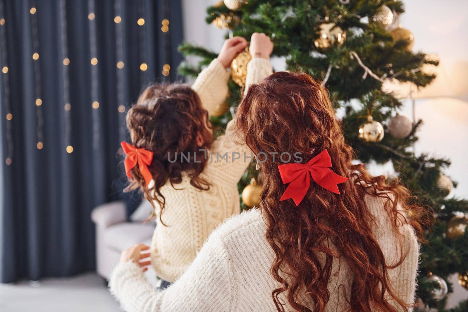 Decorating tree. Mother with her little daughter is at home.