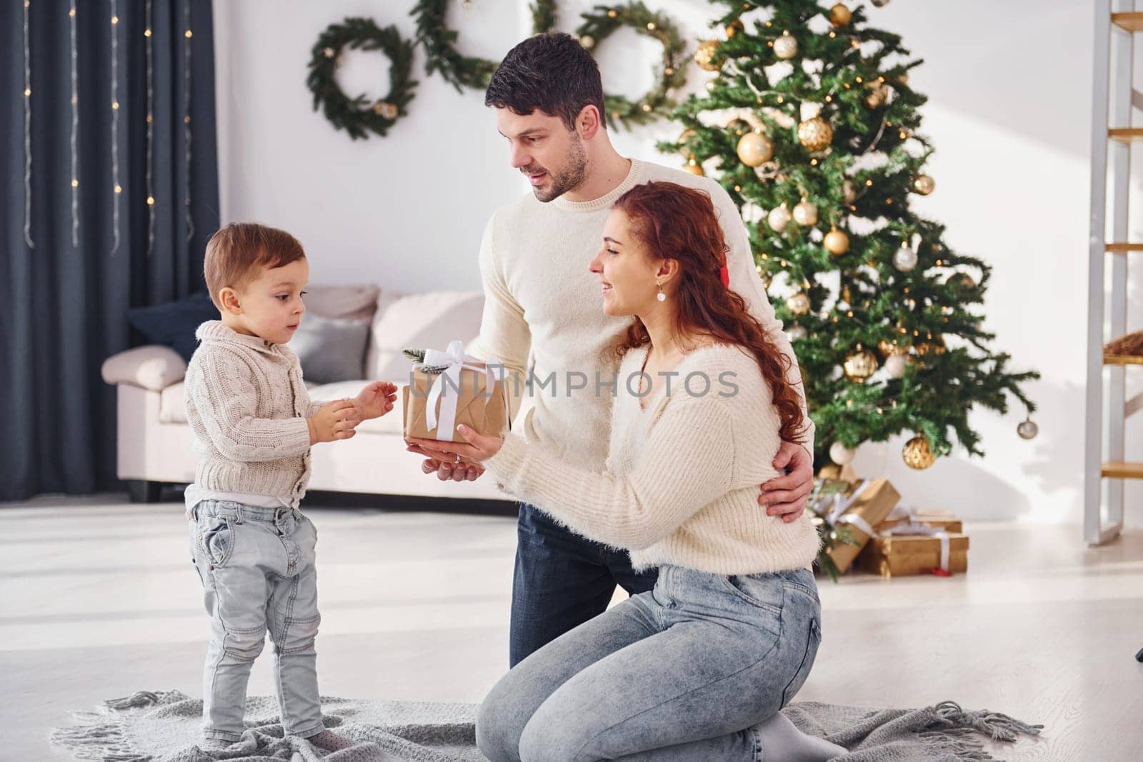 Giving present to the boy. Father and mother with son is at home celebrating new year together.