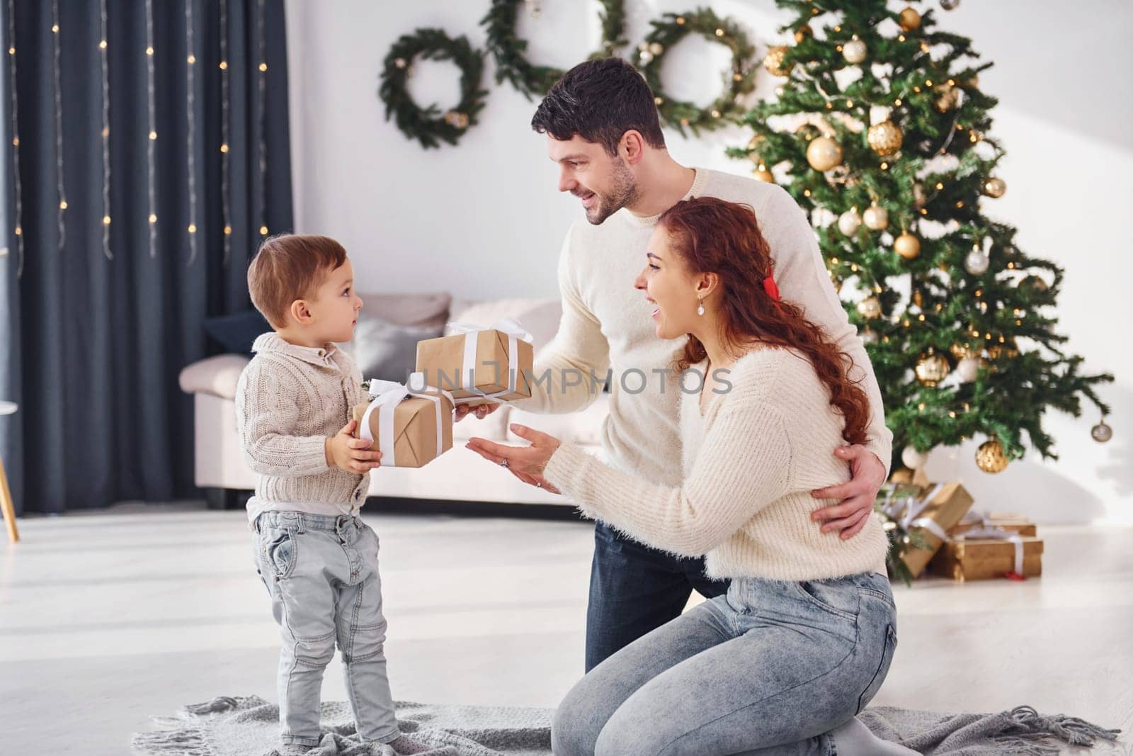 Giving present to the boy. Father and mother with son is at home celebrating new year together.