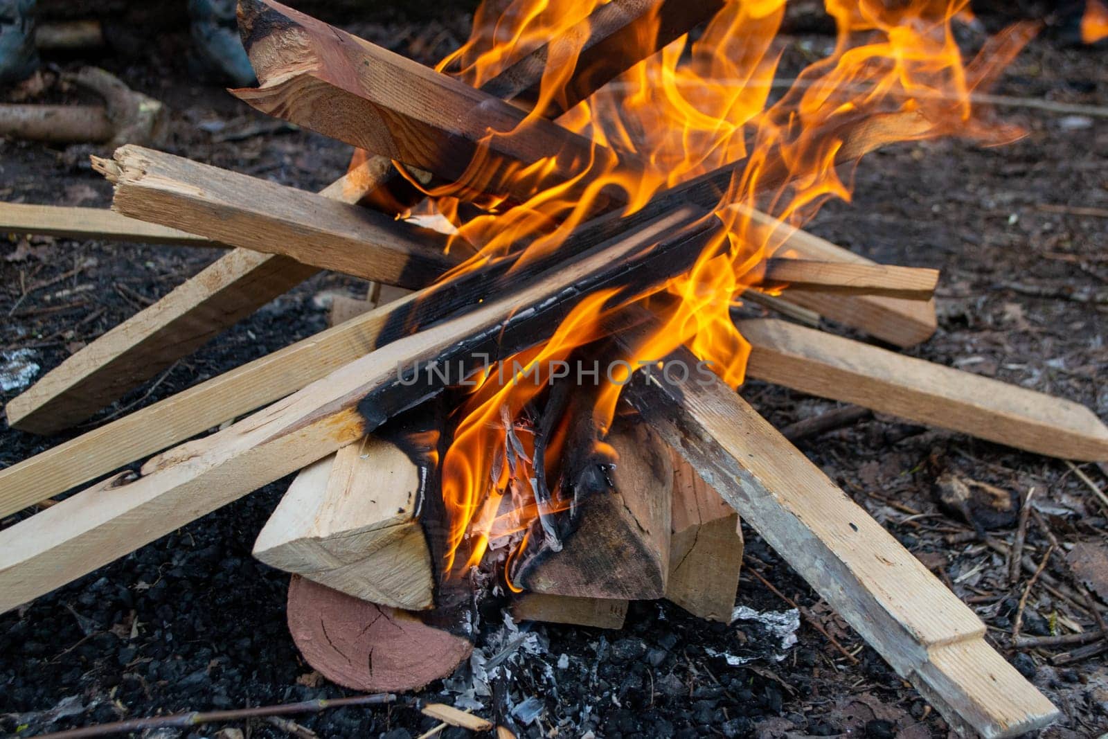 A fire burns in a campfire with a red fire in the background. High quality photo