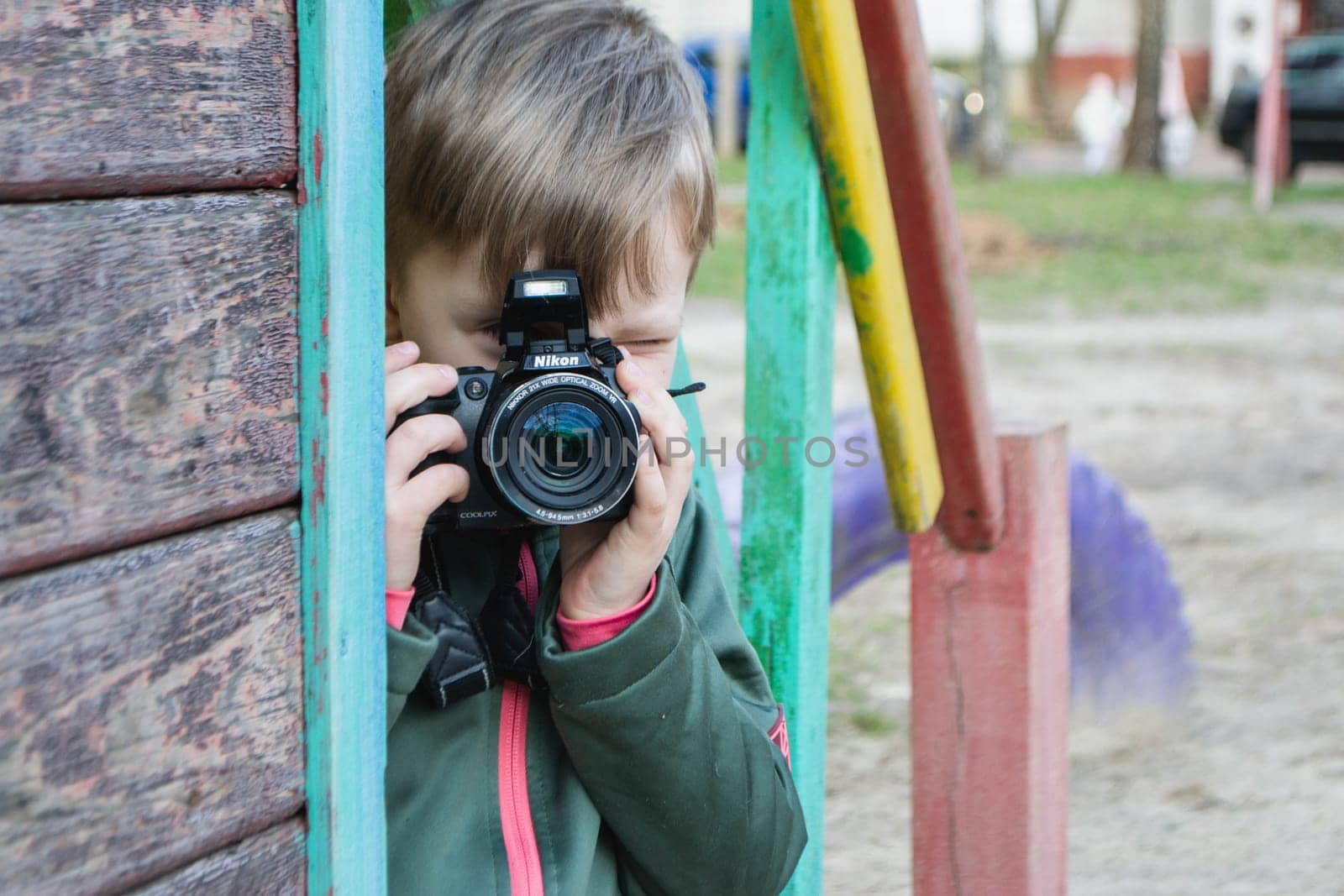 kid on the street in a jacket with an film camera. High quality photo