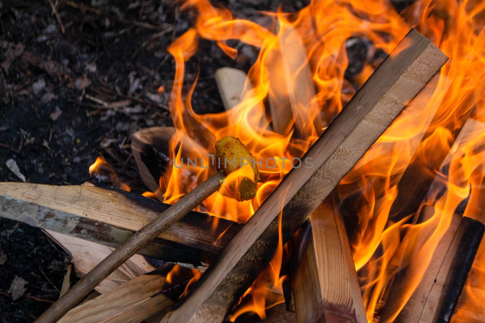 A fire burns in a campfire with a red fire in the background. High quality photo