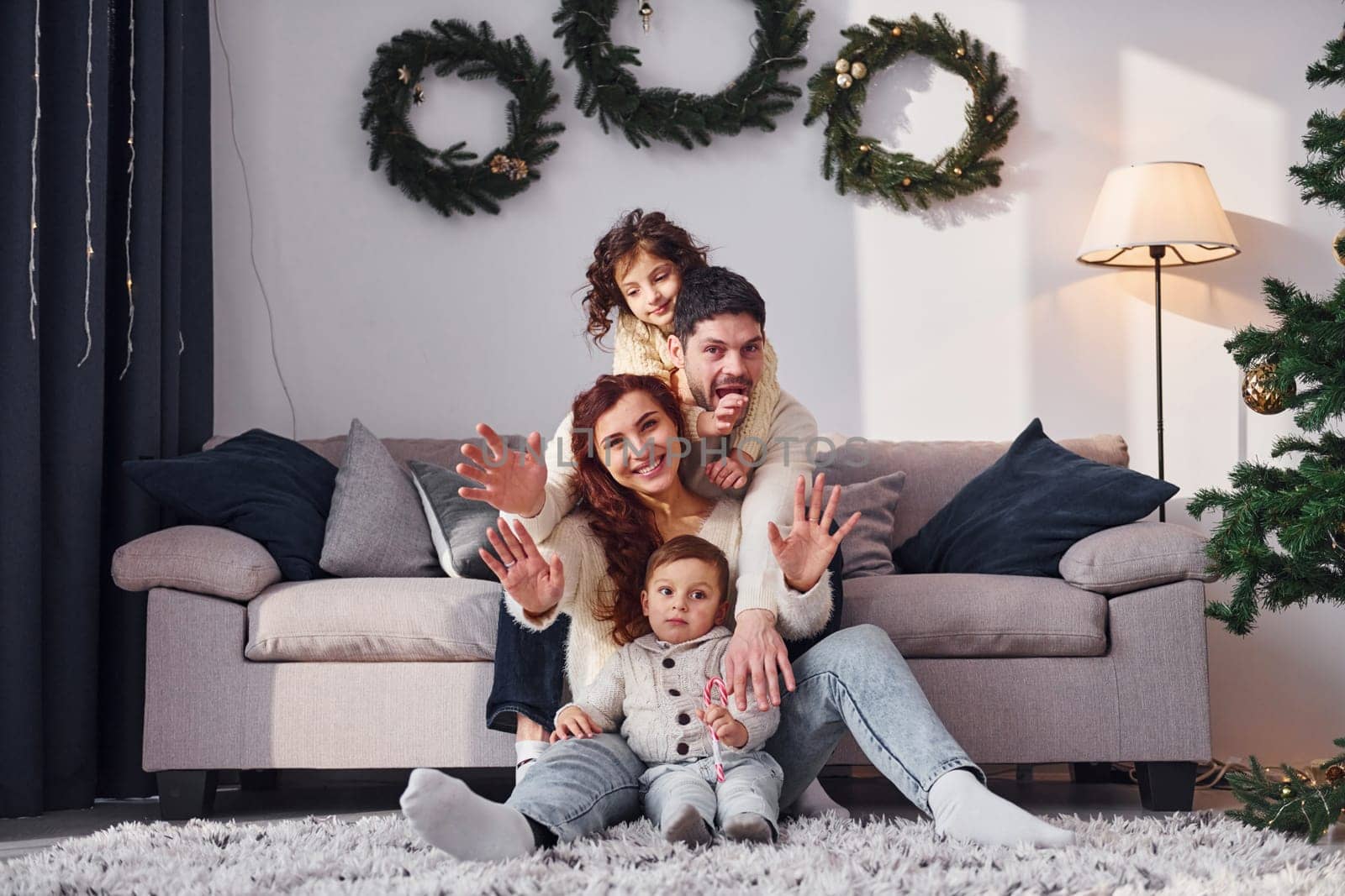 Sitting near sofa. Family celebrating new year with their children at home.
