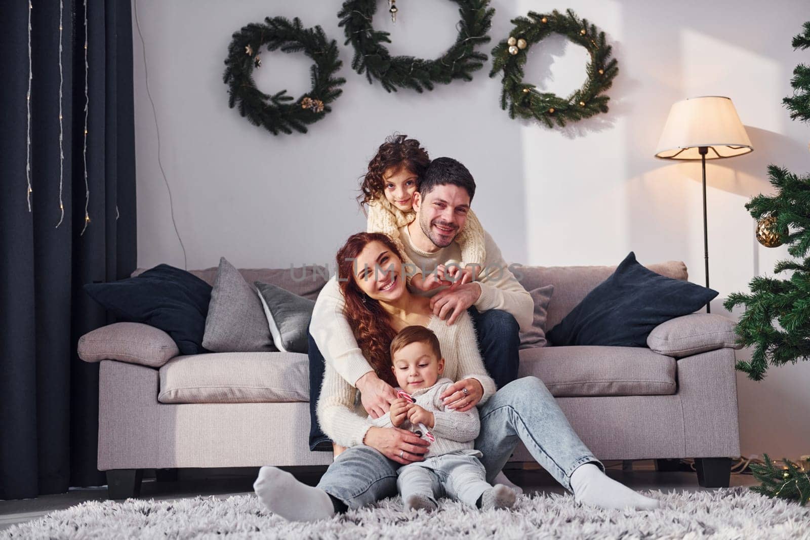 Sitting near sofa. Family celebrating new year with their children at home.