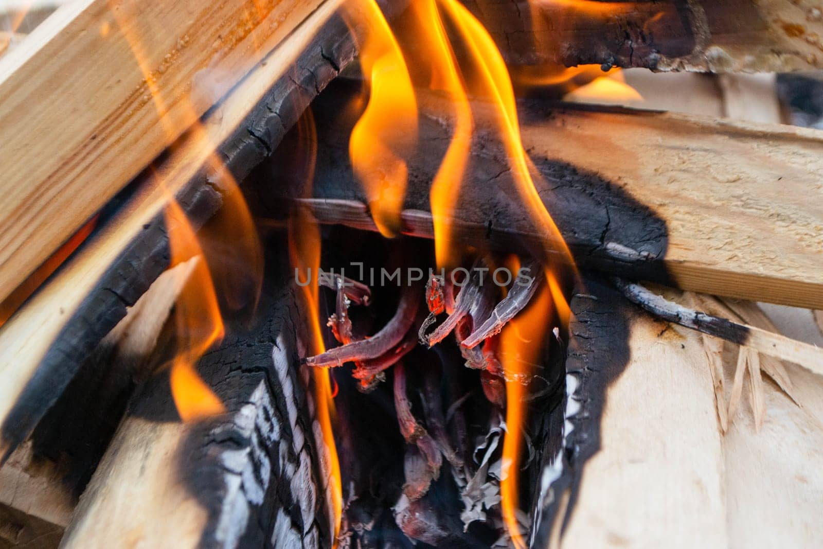 A fire burns in a campfire with a red fire in the background. High quality photo