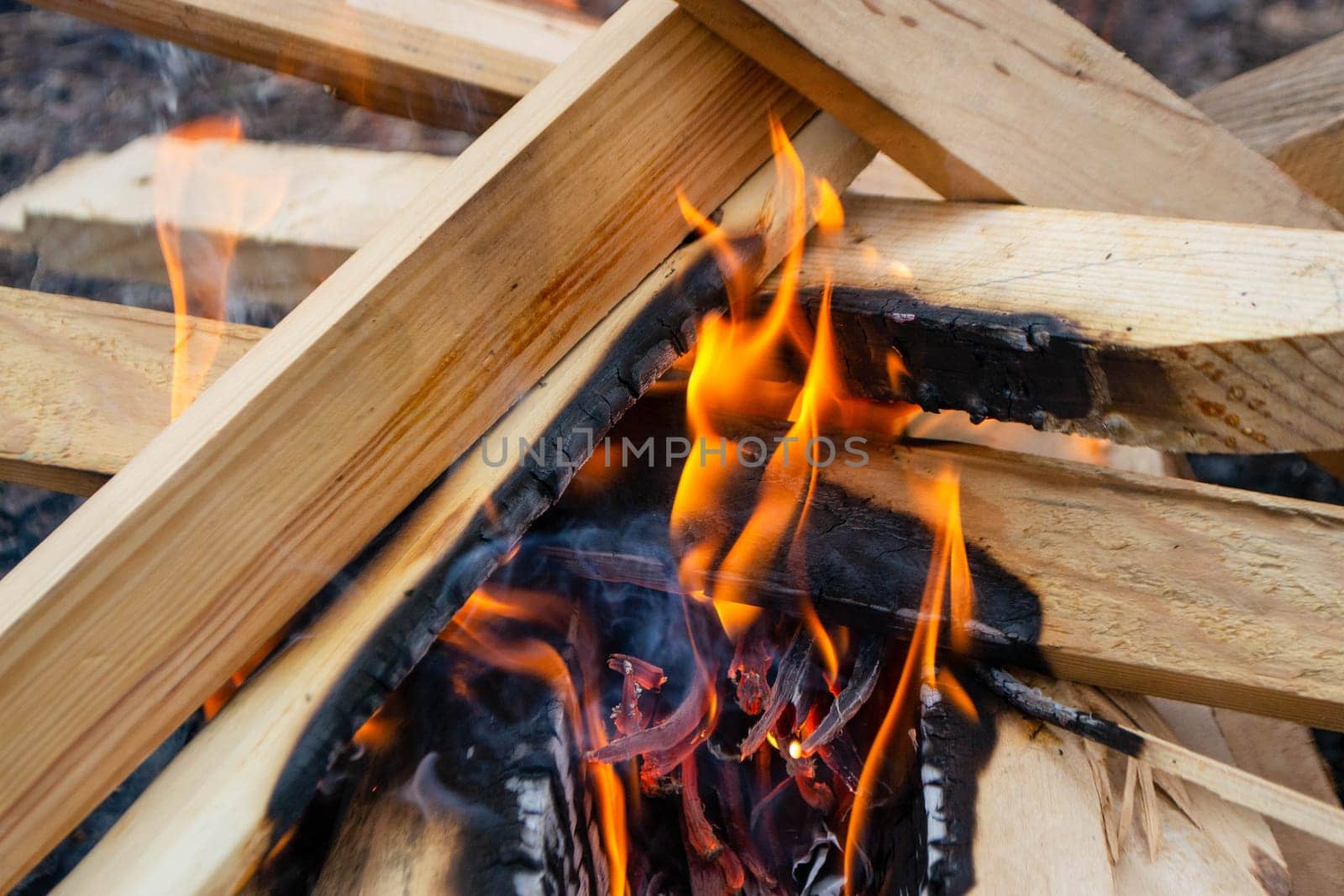 A fire burns in a campfire with a red fire in the background. High quality photo