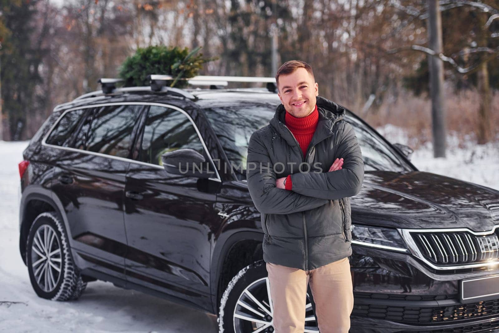 Front view. Man with little green fir is outdoors near his car. Conception of holidays.