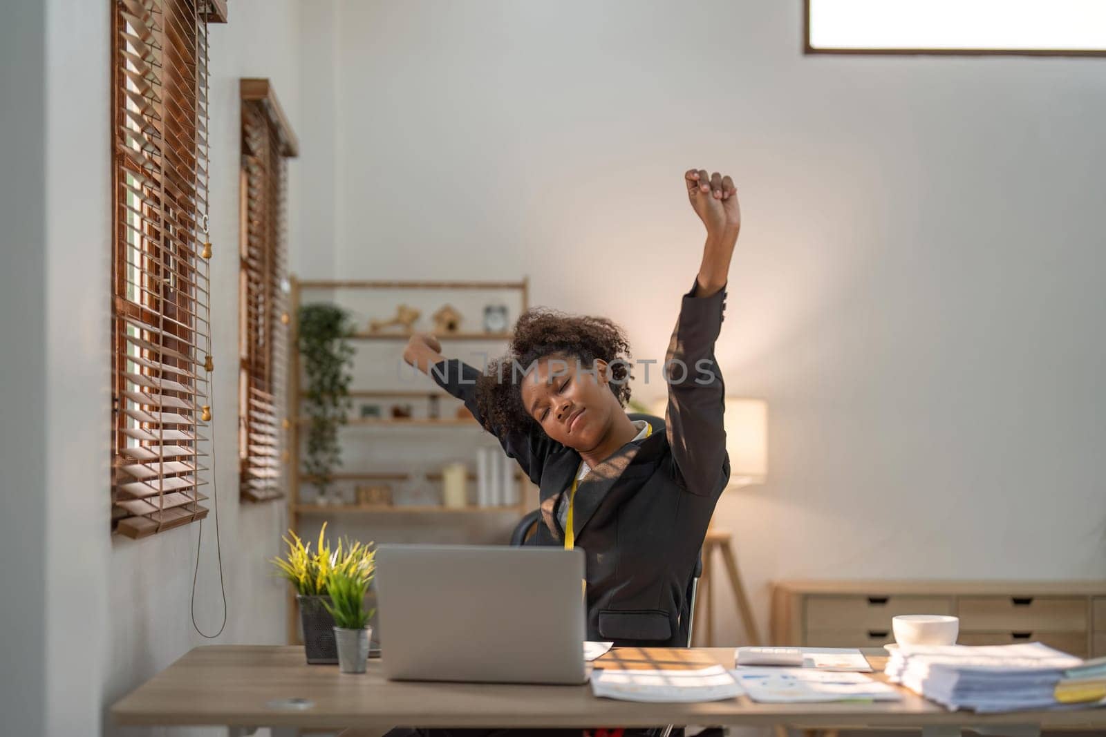 Black business woman stretches in office at workplace by nateemee