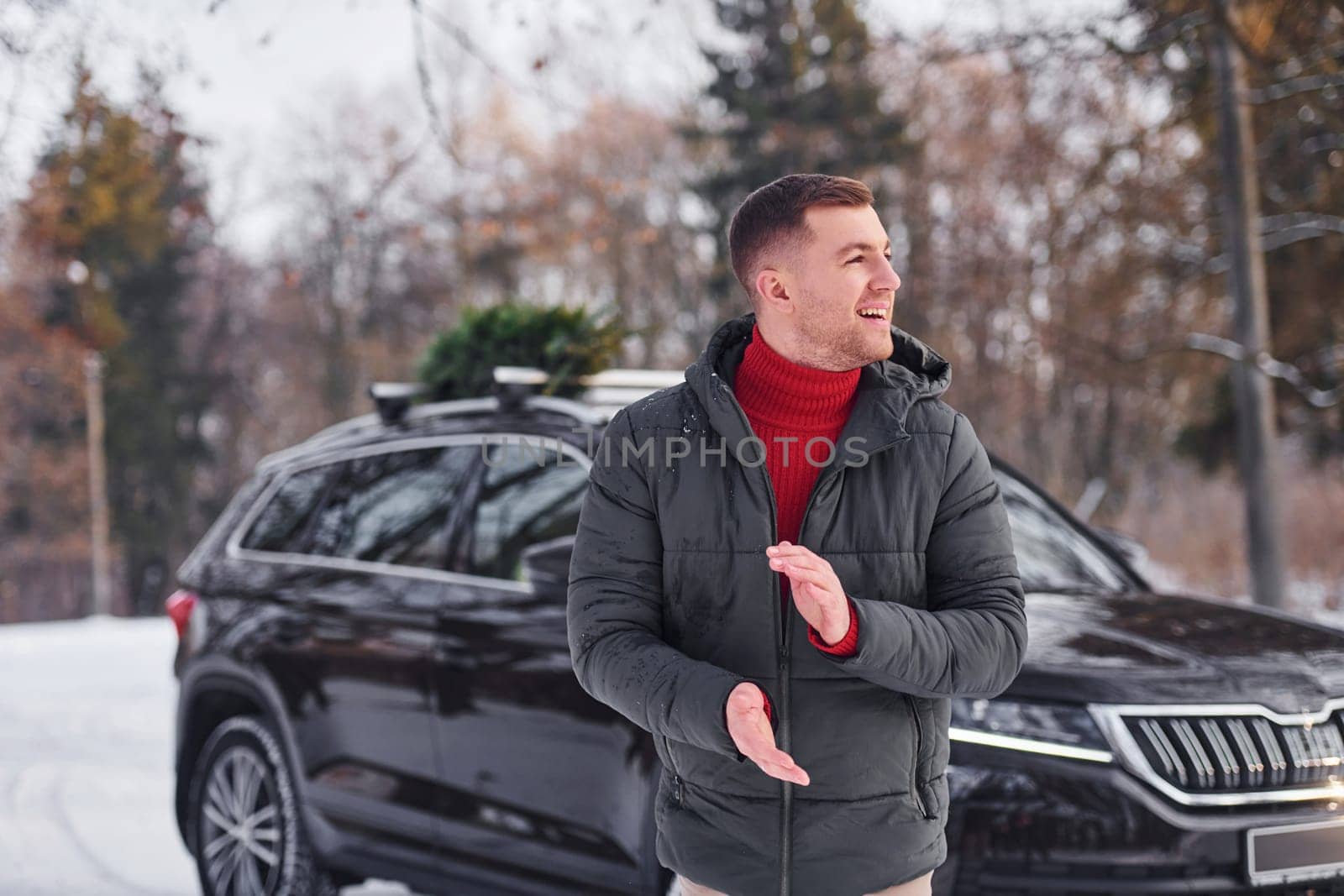 Man with little green fir is outdoors near his car. Conception of holidays.