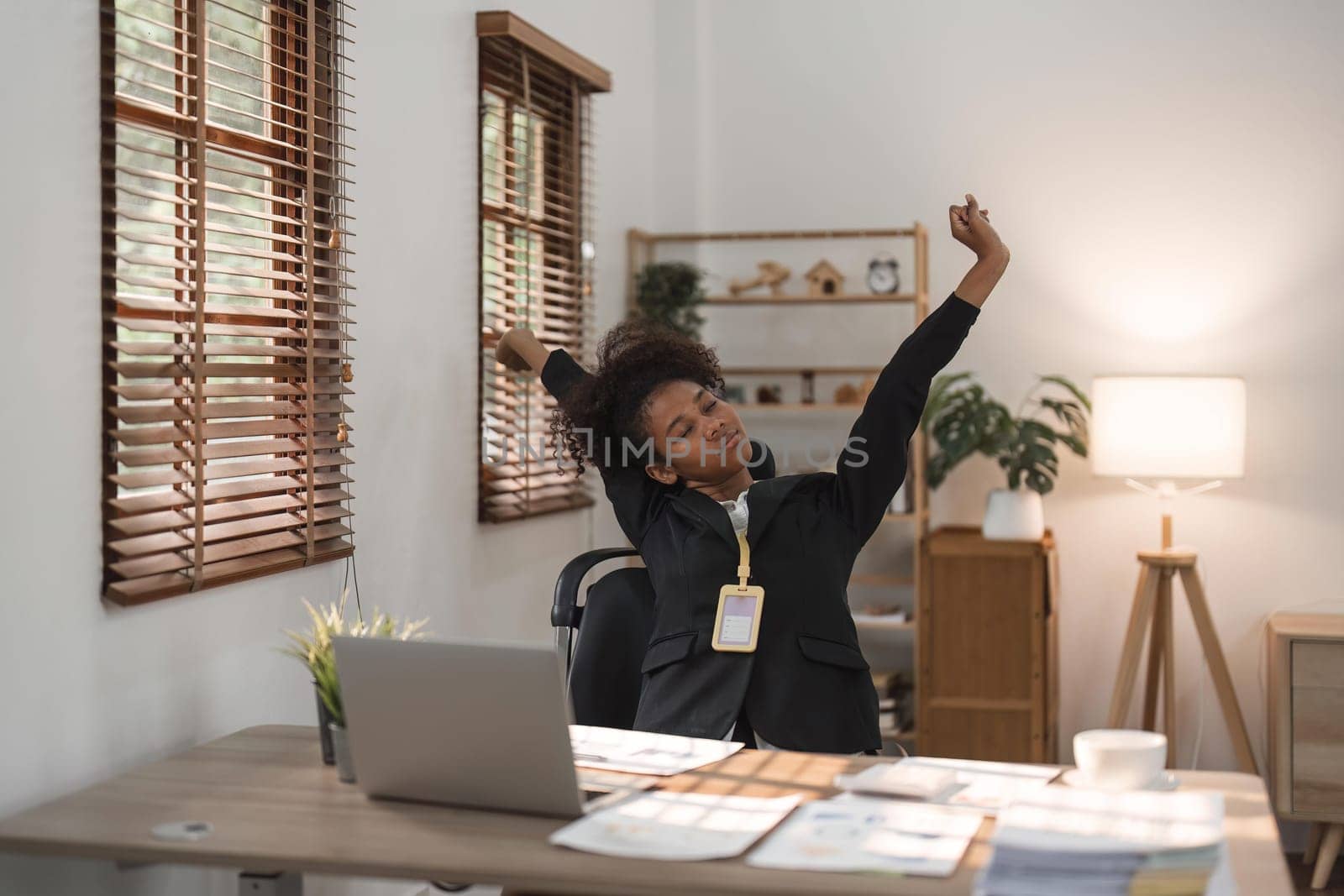 Black business woman stretches in office at workplace.