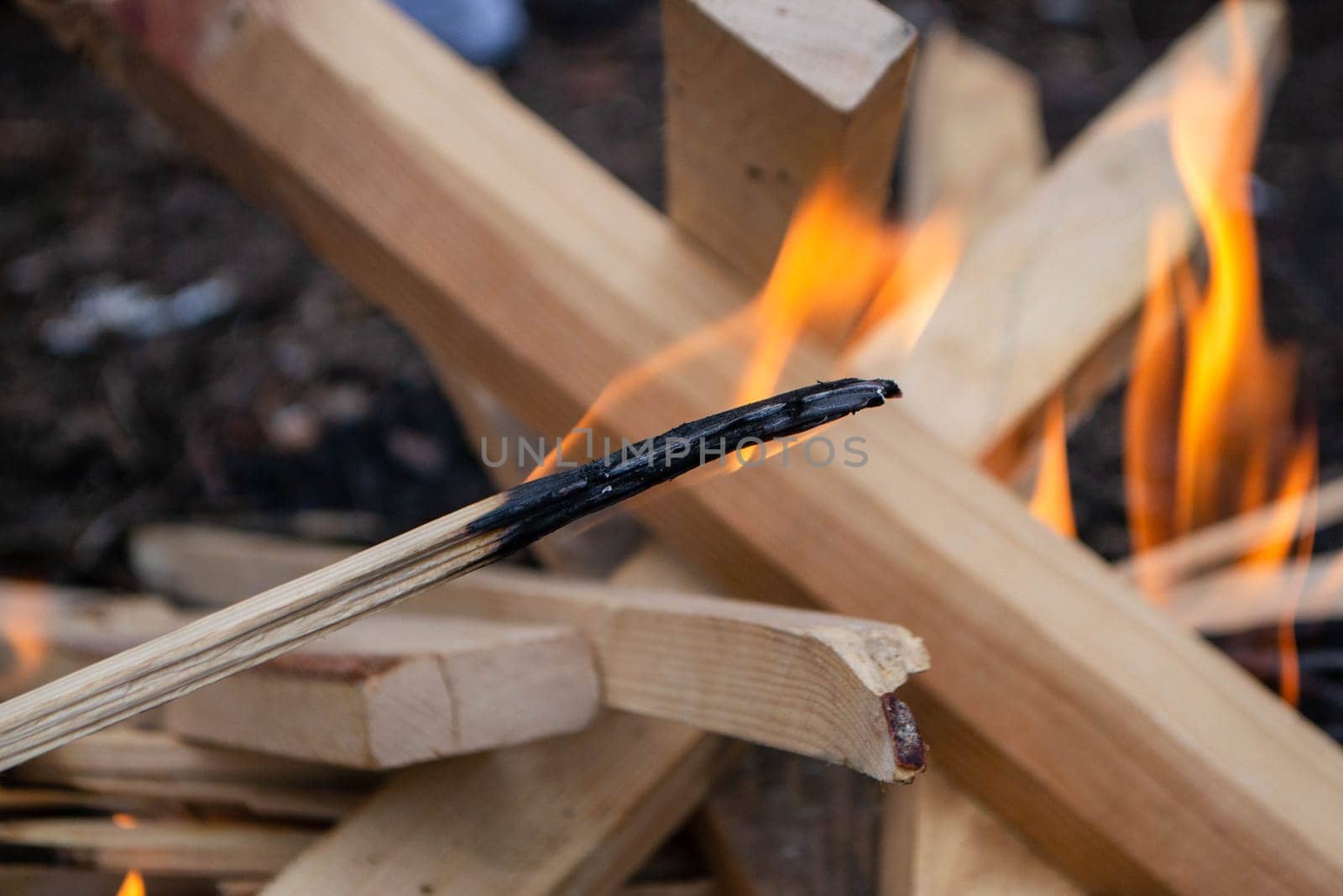 A fire burns in a campfire with a red fire in the background. High quality photo