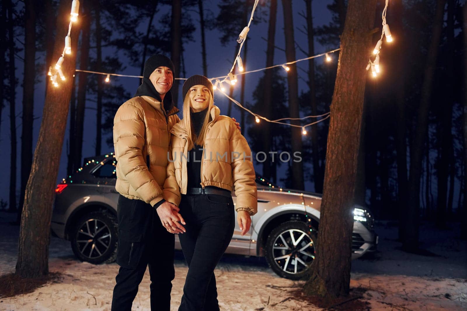 Holding by the hands. Couple standing in the forest and celebrating New year.