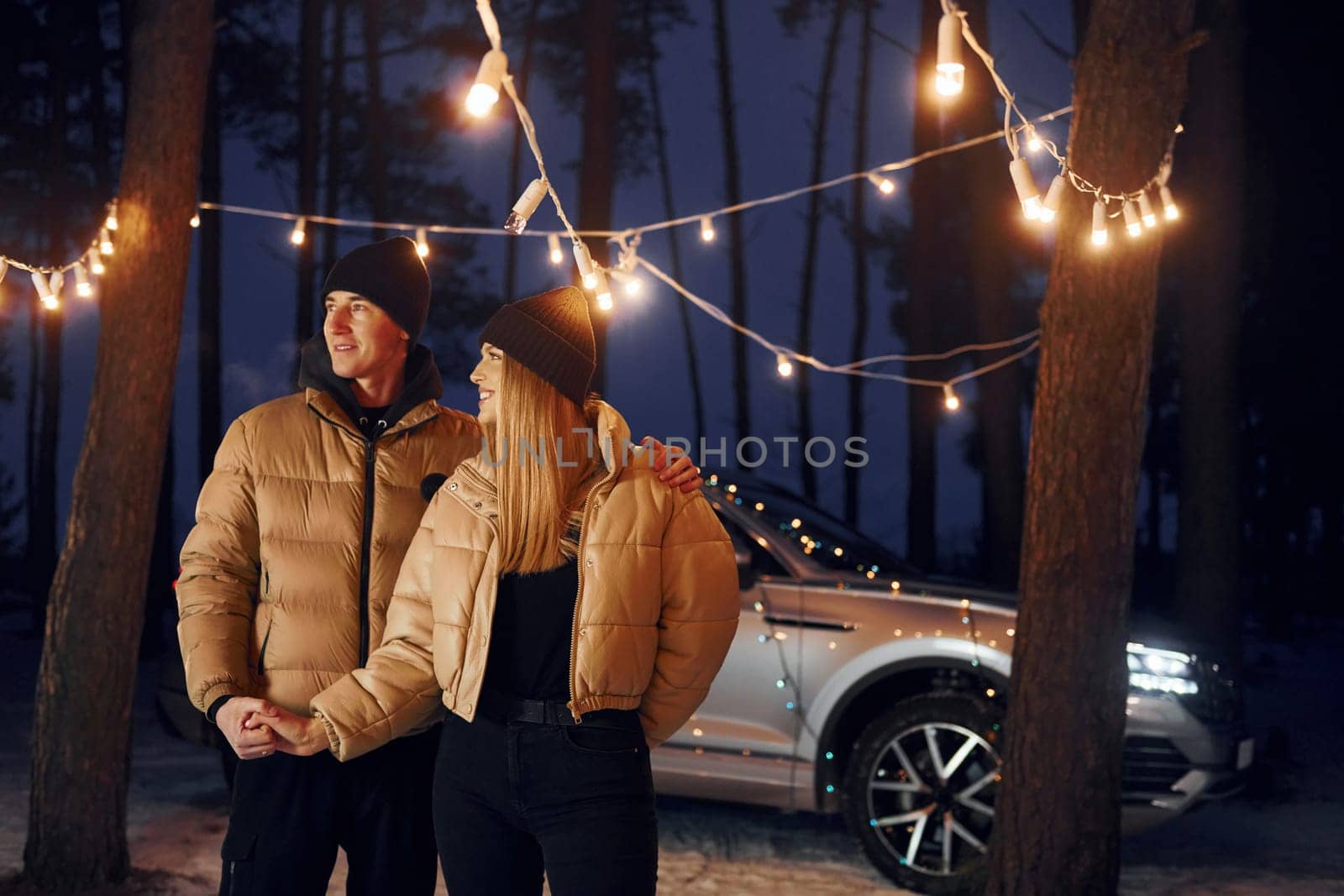 Holding by the hands. Couple standing in the forest and celebrating New year.