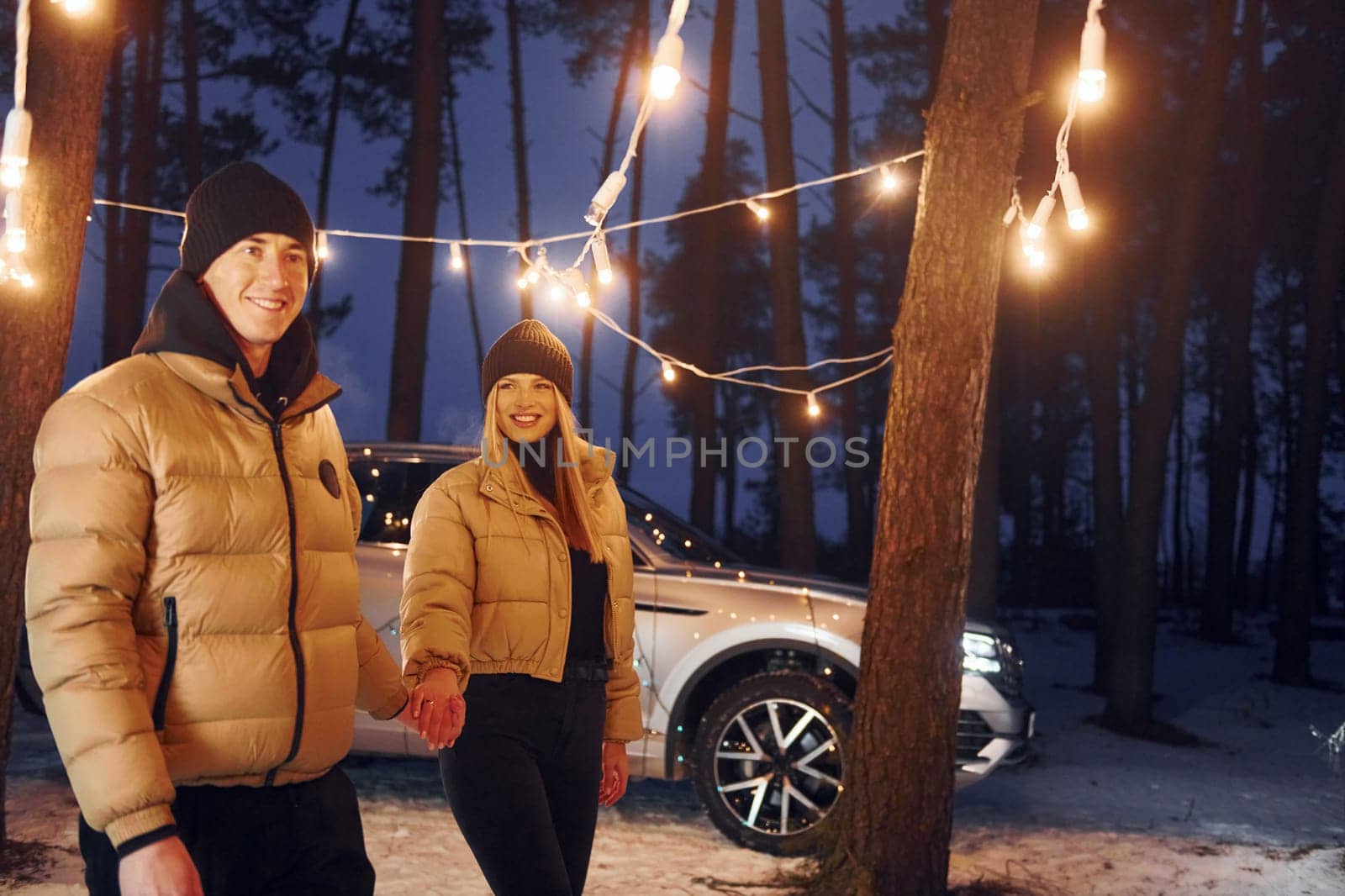 Holding by the hands. Couple standing in the forest and celebrating New year.