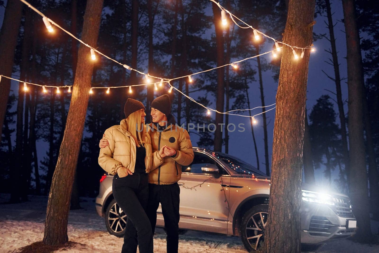 Automobile parked behind. Couple standing in the forest and celebrating New year.