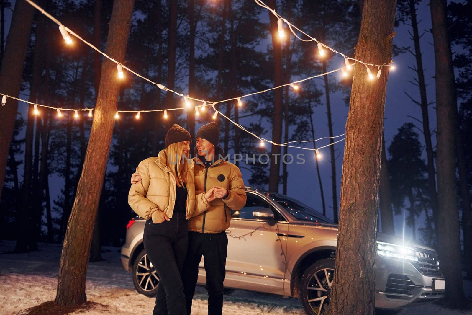 Automobile parked behind. Couple standing in the forest and celebrating New year.