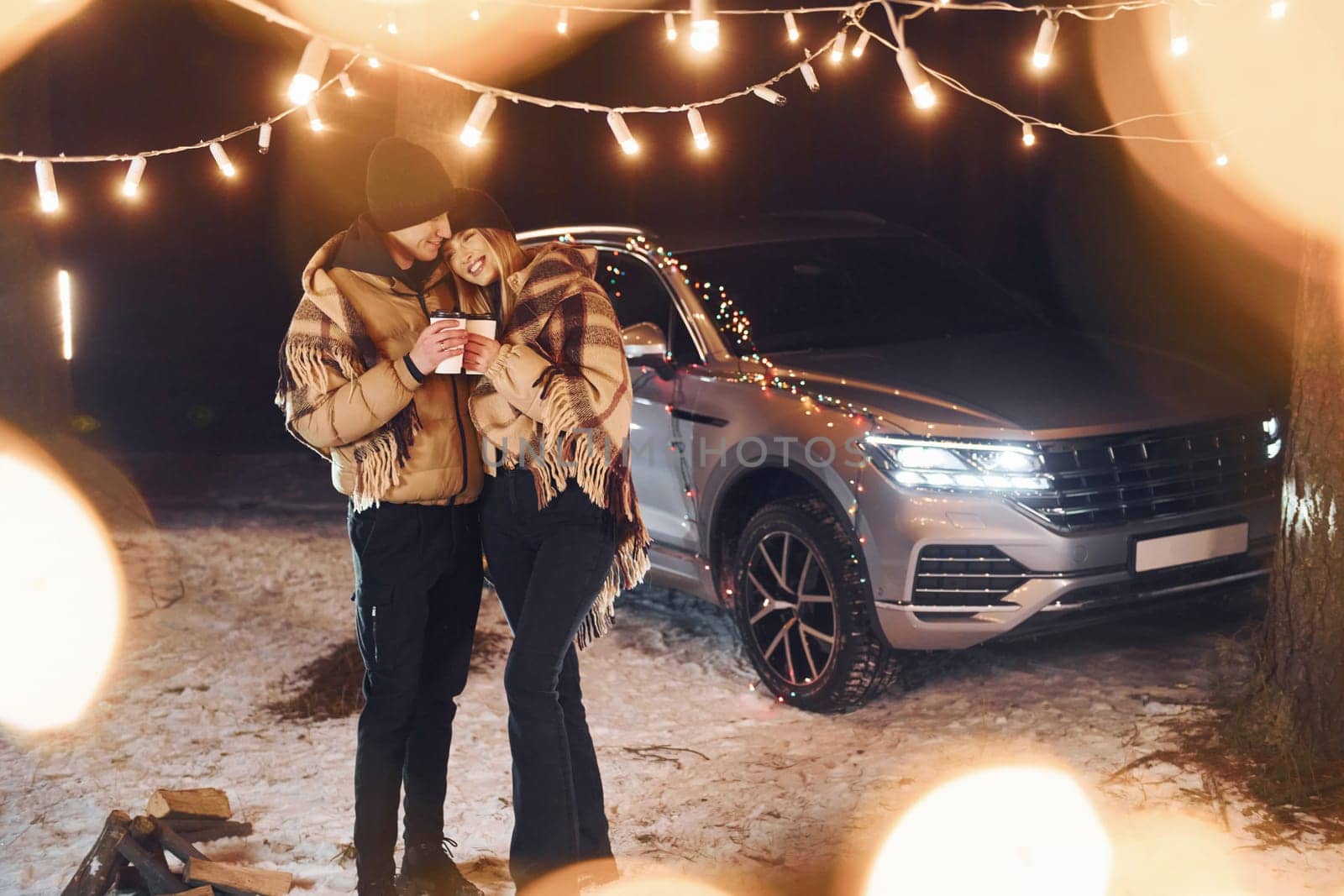 With warm drinks. Couple standing in the forest and celebrating New year.