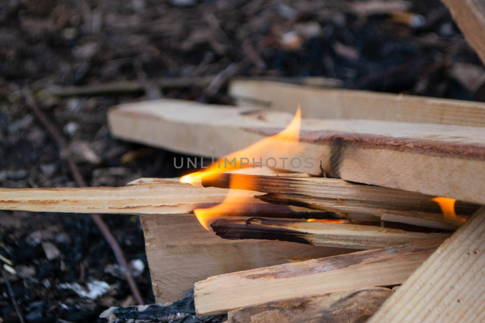 A fire burns in a campfire with a red fire in the background. High quality photo