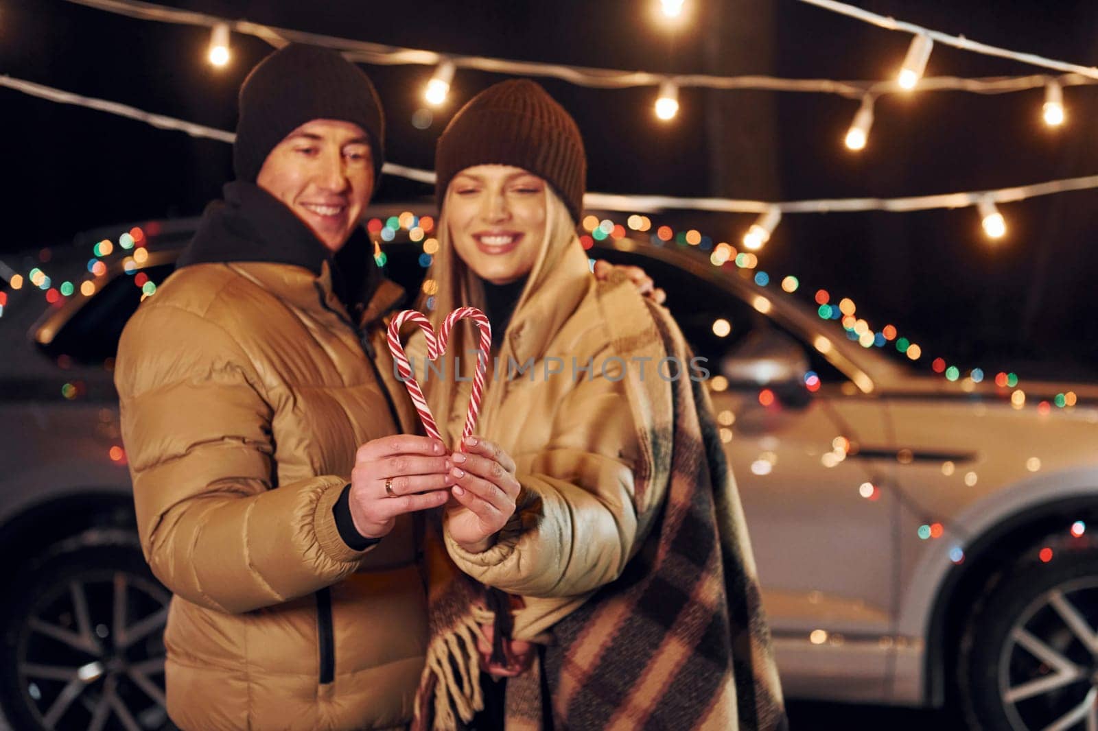 Holding candies. Couple standing in the forest and celebrating New year.