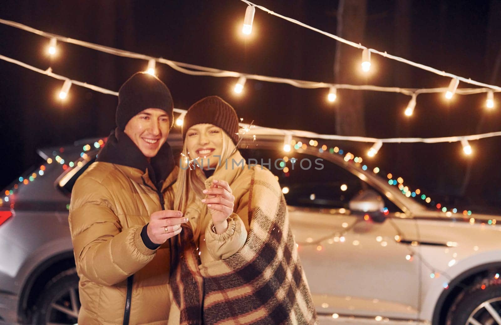 Holding sparklers. Couple standing in the forest and celebrating New year.