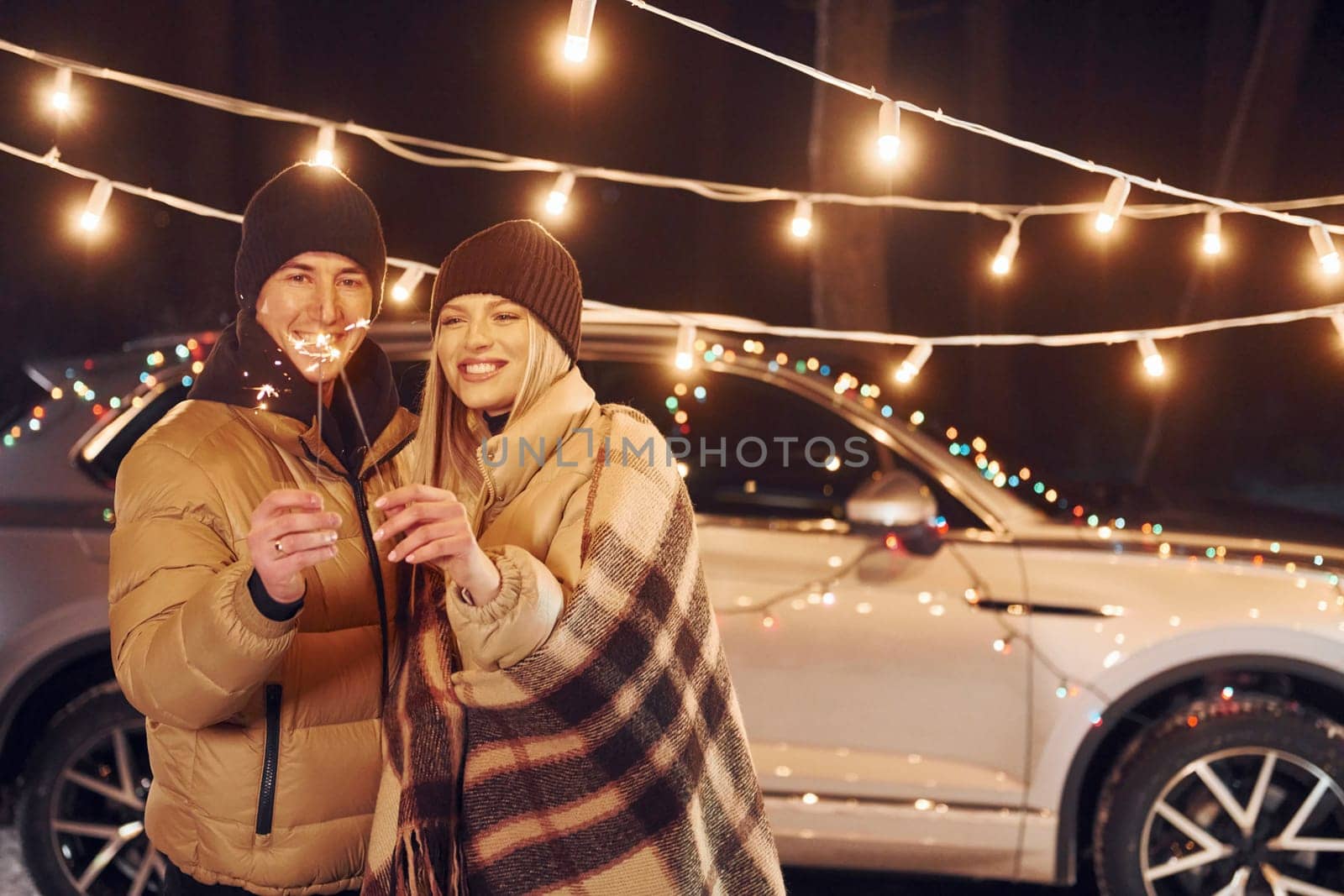 Holding sparklers. Couple standing in the forest and celebrating New year.