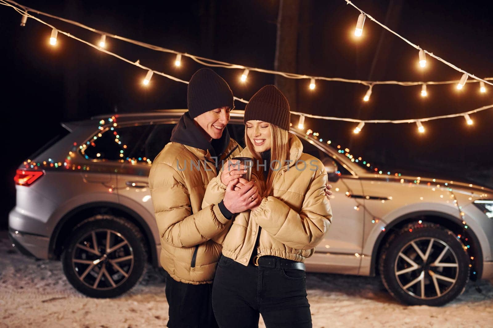 Yellow colored lighting. Couple standing in the forest and celebrating New year.
