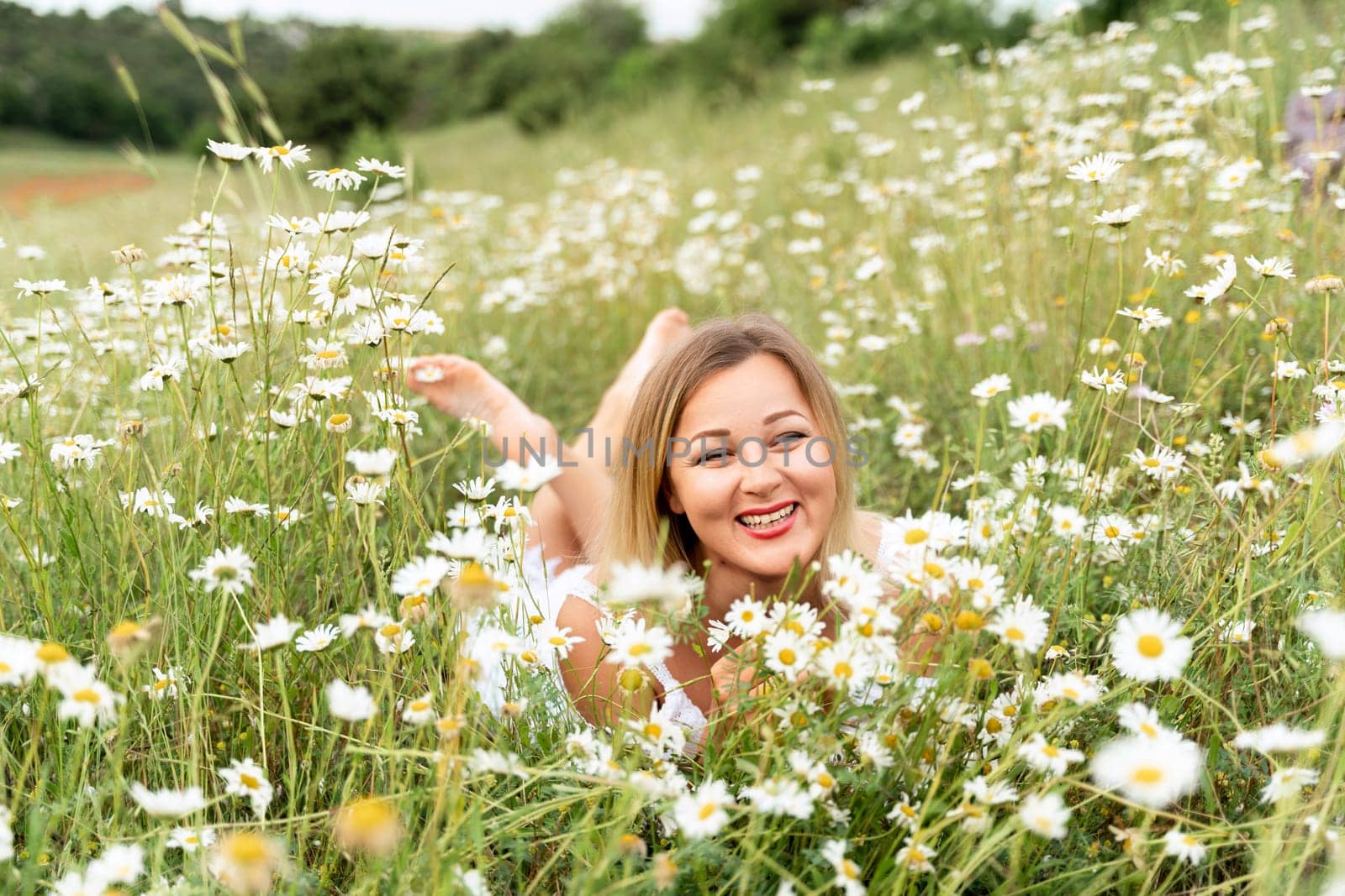 A woman lies in a chamomile field, dressed in a white dress by Matiunina