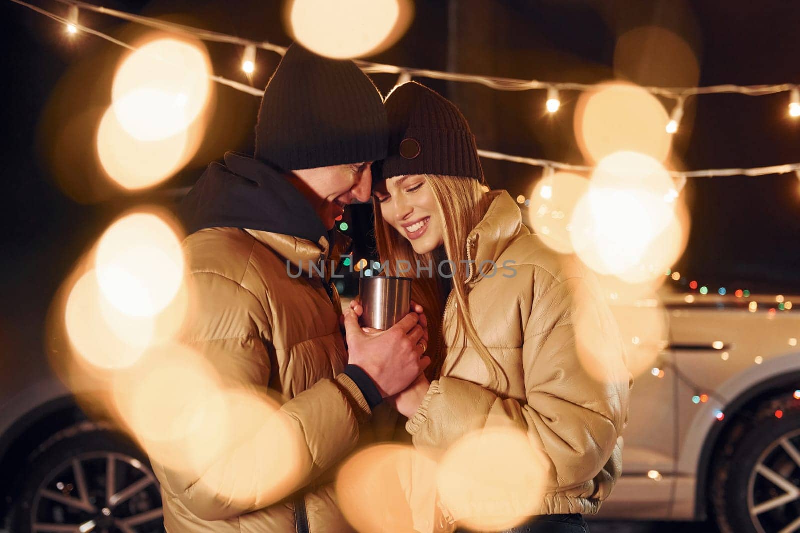 Yellow colored lighting. Couple standing in the forest and celebrating New year.