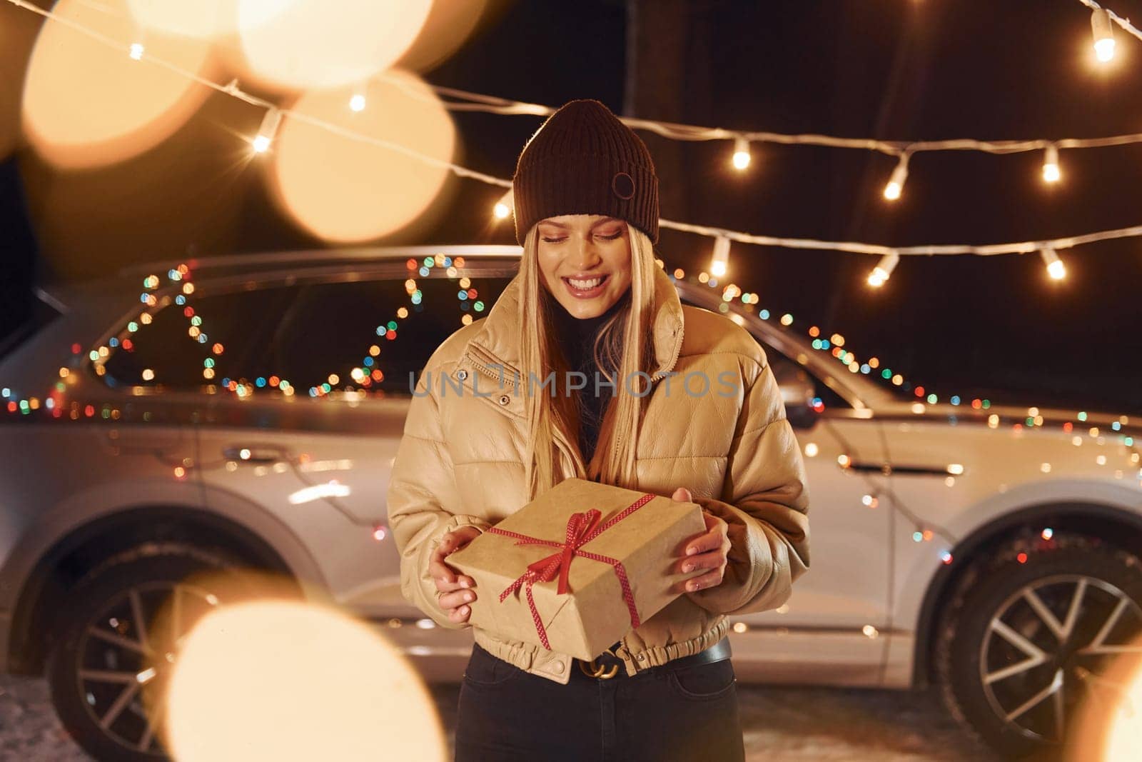 Holding gift box. Woman standing in the forest and celebrating New year.