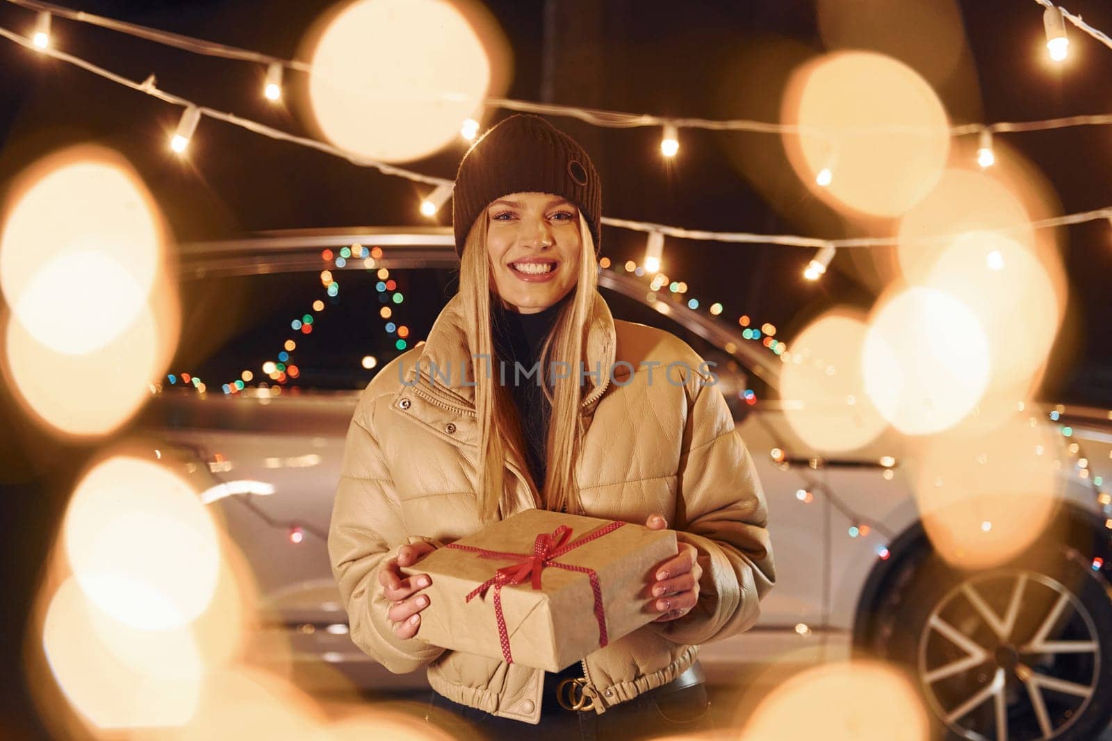 Holding gift box. Woman standing in the forest and celebrating New year.