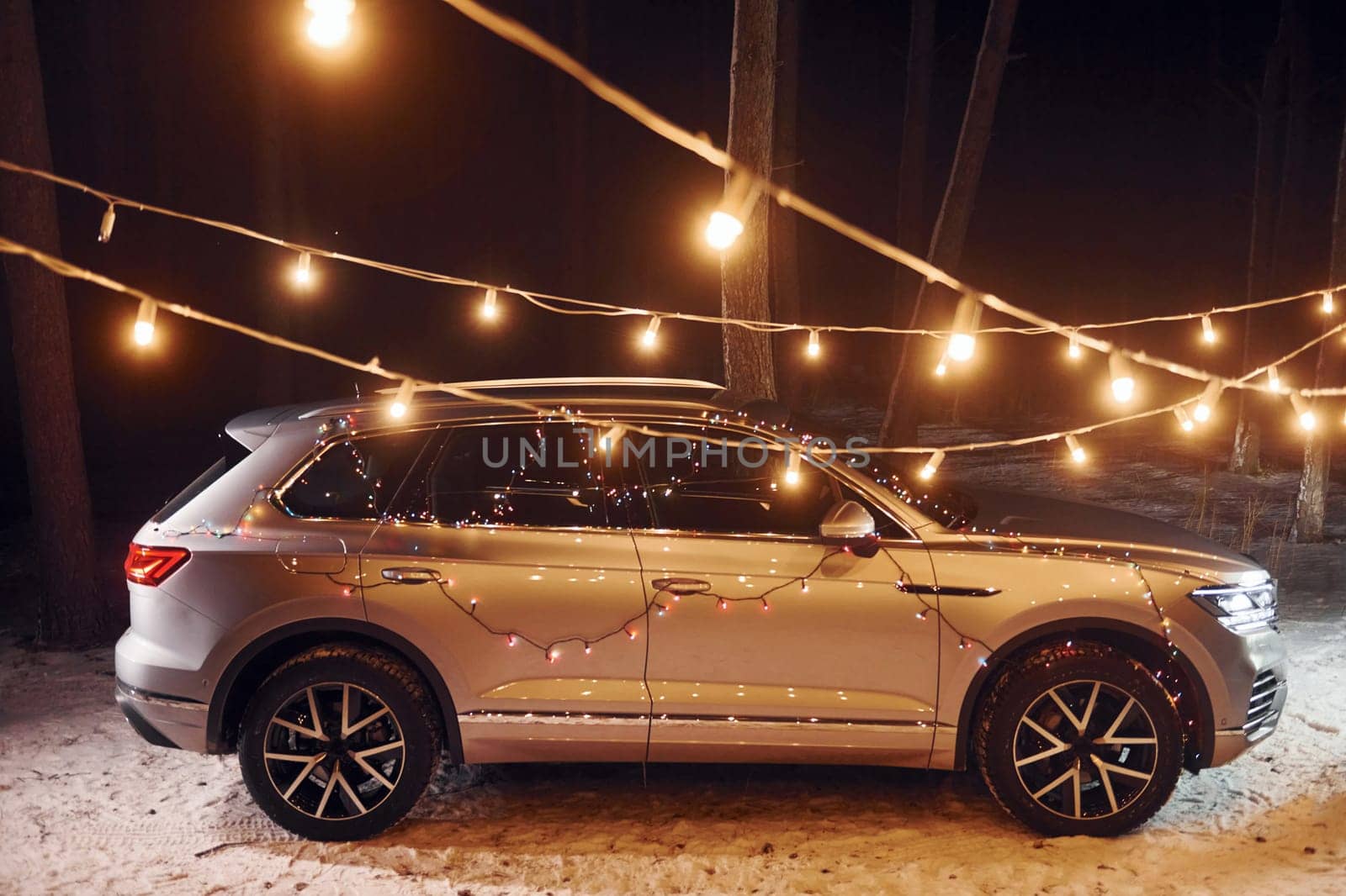 Side view. Modern silver colored automobile parked in forest with holiday decoration.