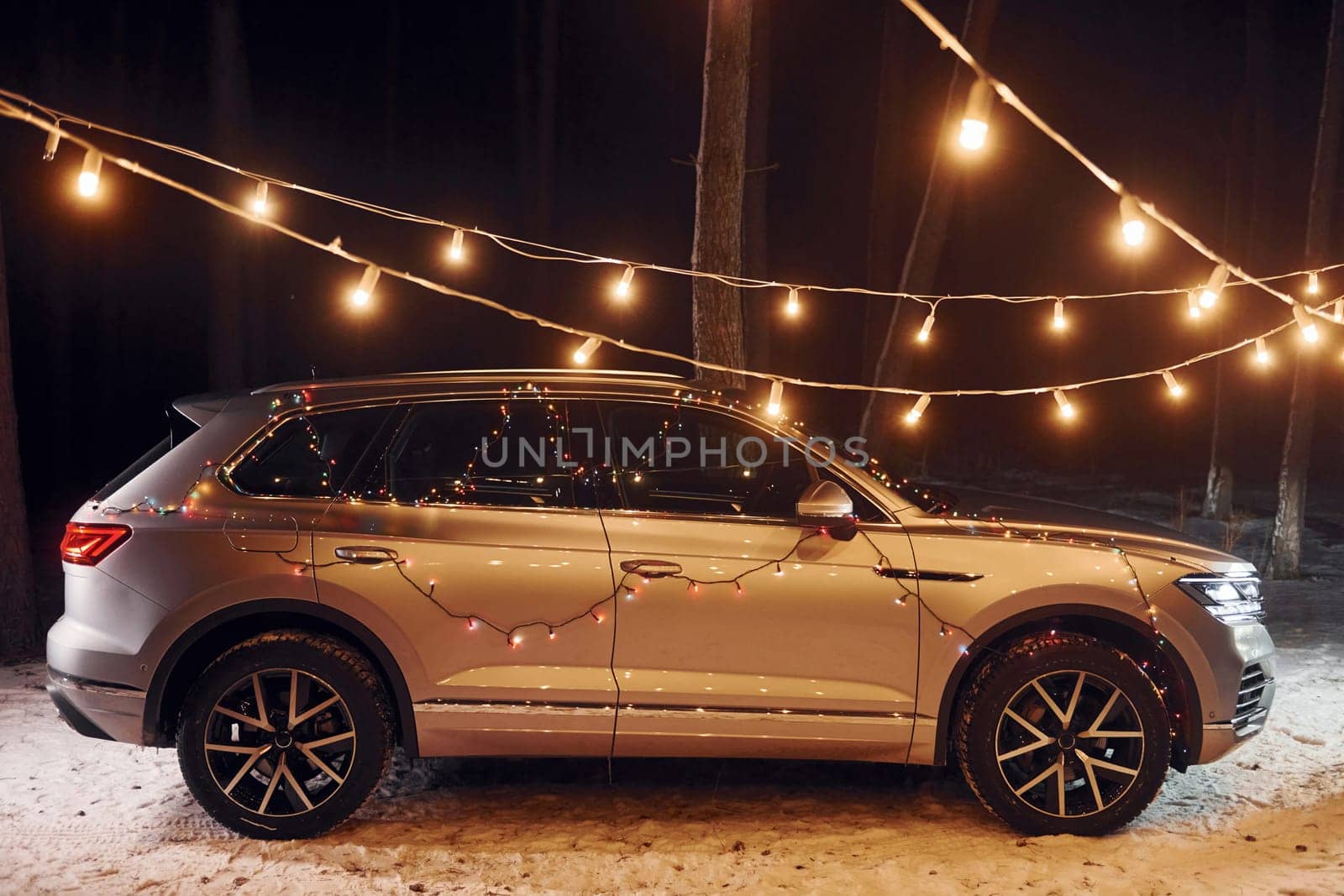 Side view. Modern silver colored automobile parked in forest with holiday decoration.