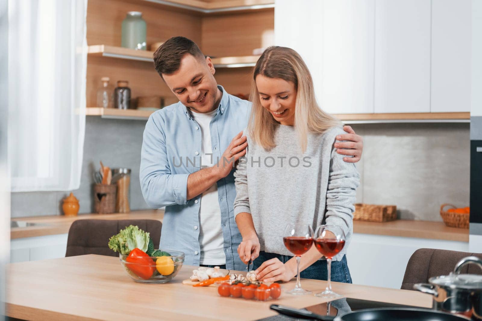 Cute people. Couple preparing food at home on the modern kitchen.