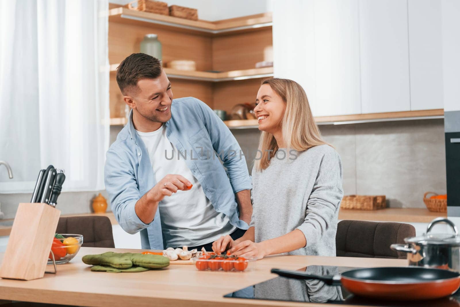 Helping each other. Couple preparing food at home on the modern kitchen.