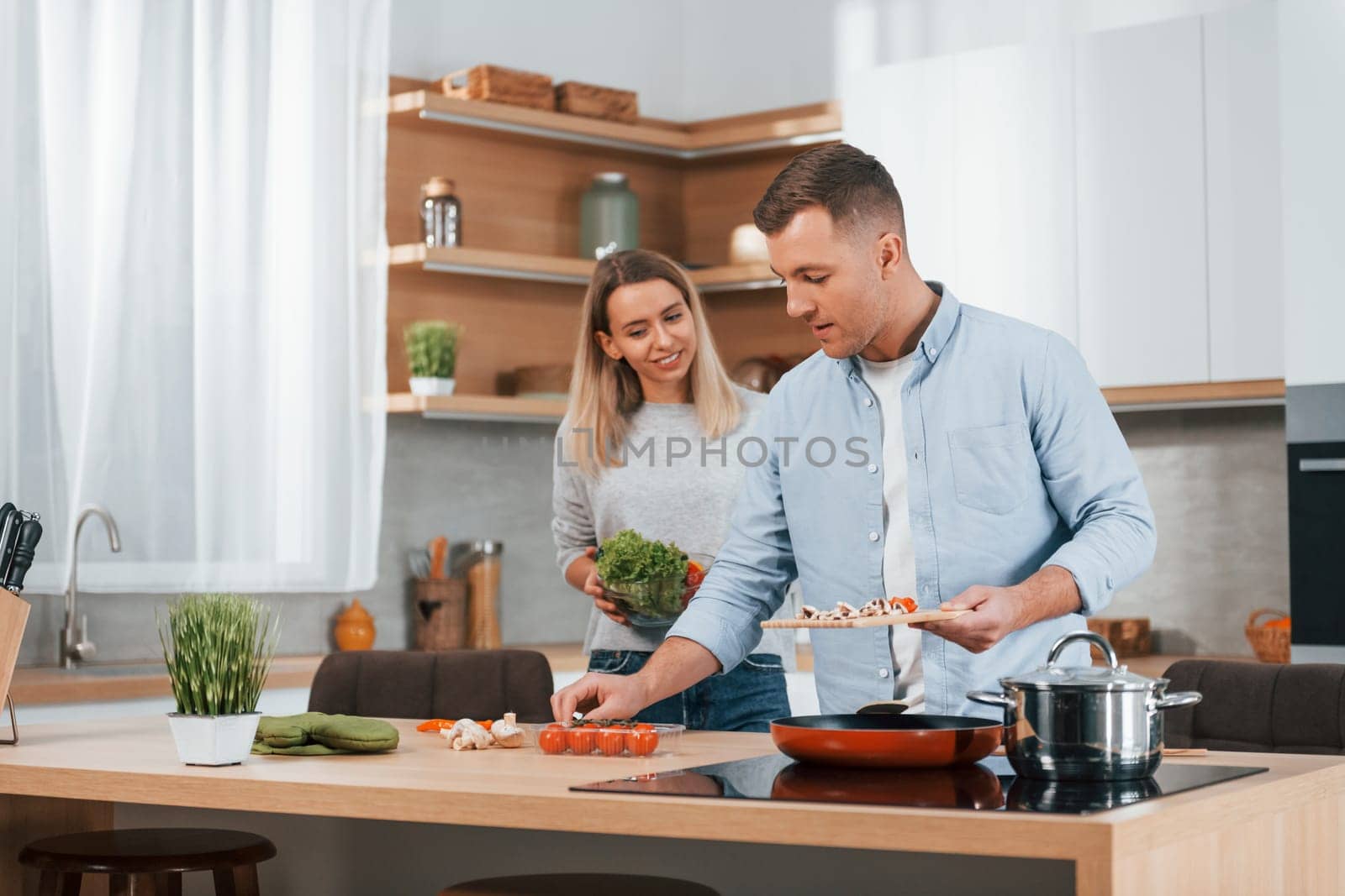 Man standing by the table. Couple preparing food at home on the modern kitchen.