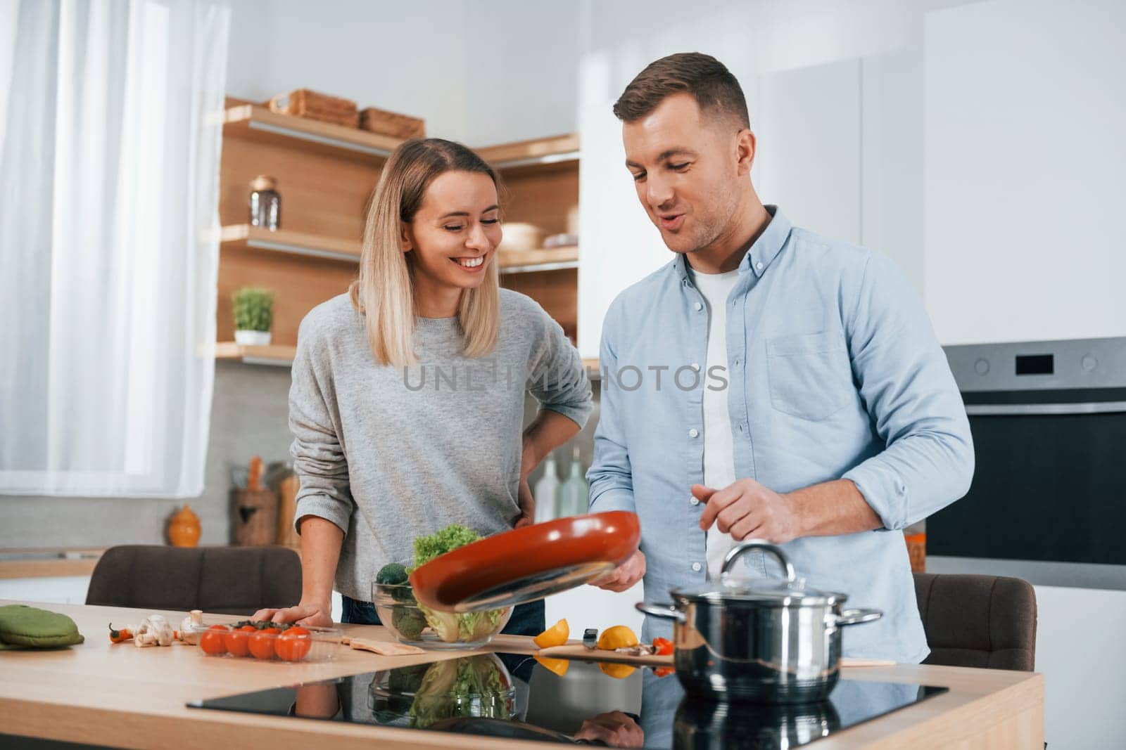 Delicious dinner. Couple preparing food at home on the modern kitchen by Standret