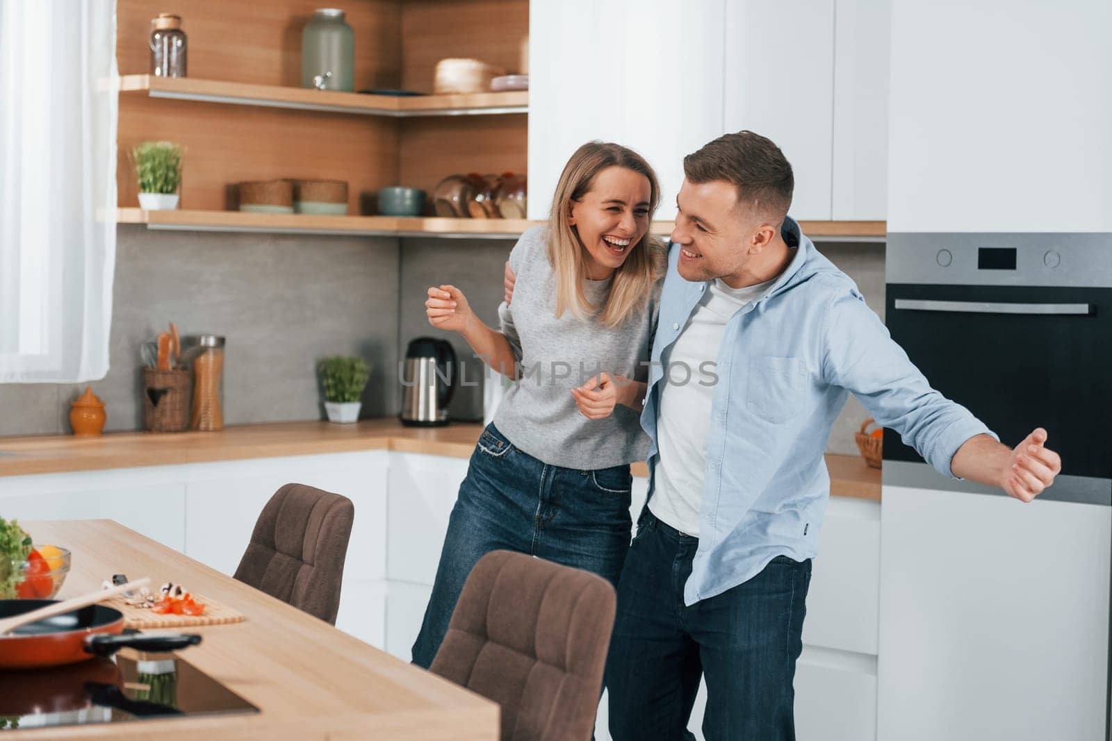 Positive emotions. Couple preparing food at home on the modern kitchen.