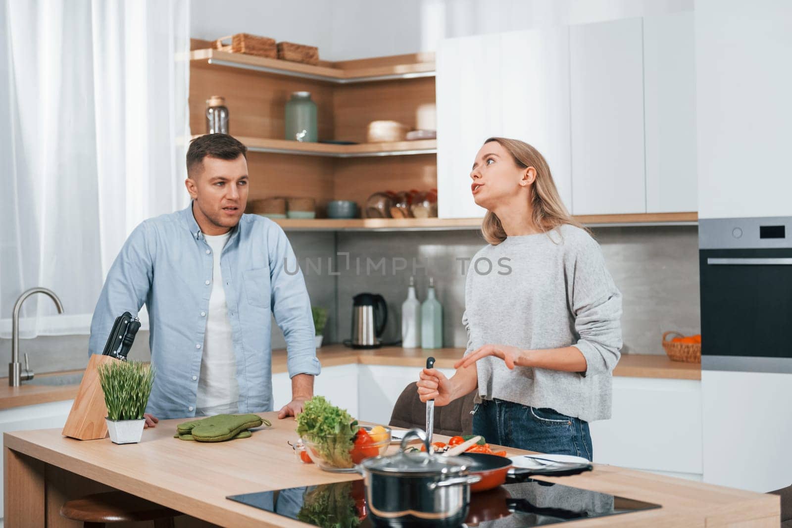 Arguing with each other. Couple preparing food at home on the modern kitchen.