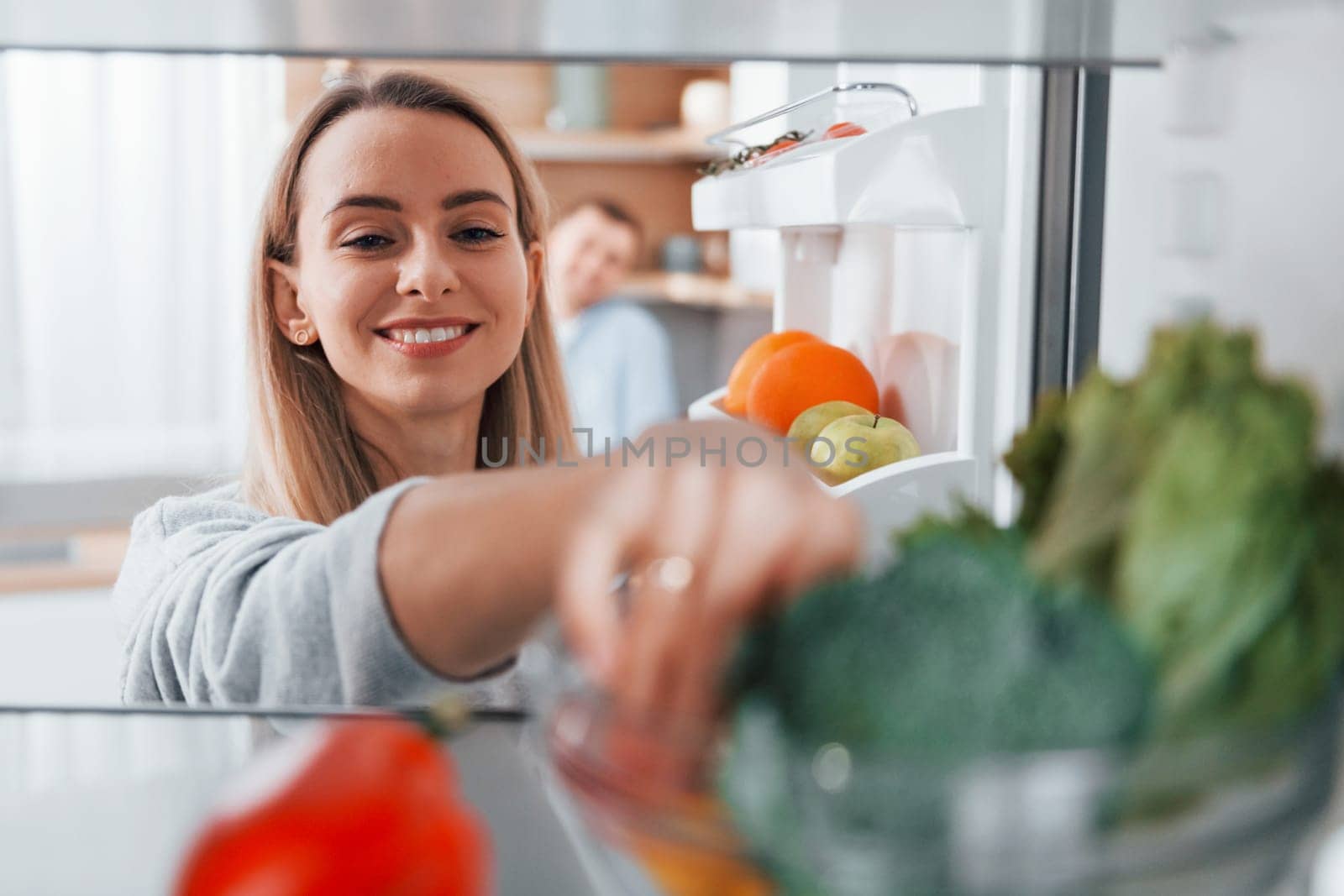 Using vegetables. Couple preparing food at home on the modern kitchen by Standret